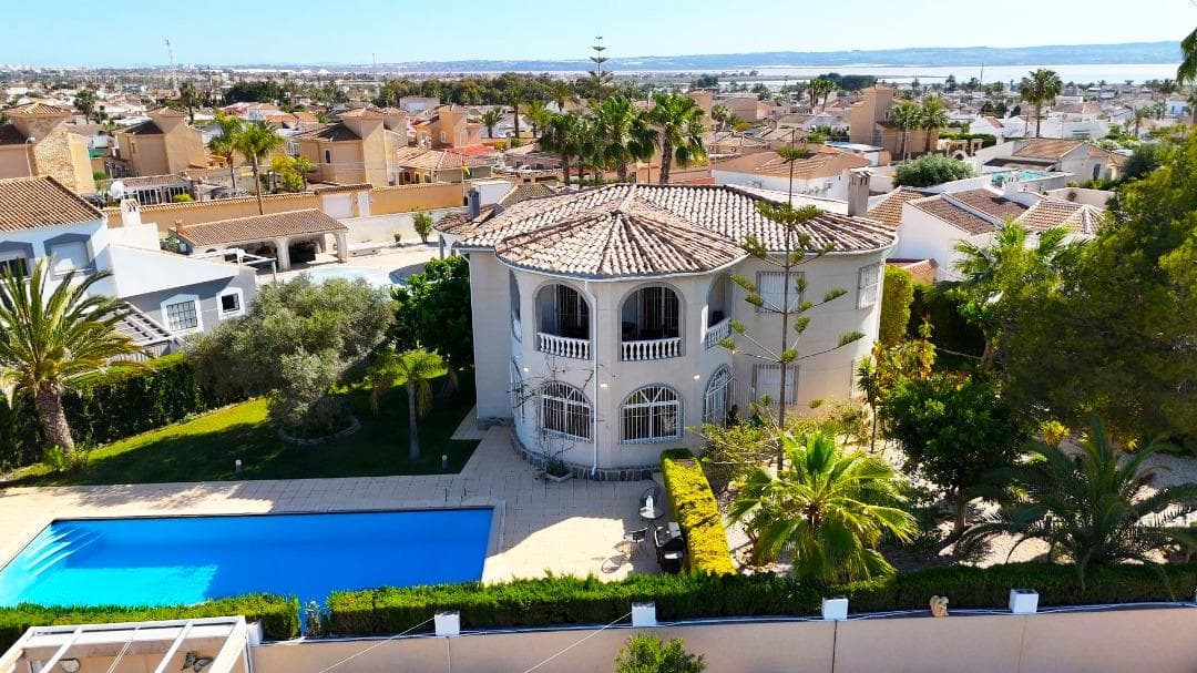 For sale is a large family 4-bedroom villa with a salon and a separate office, built on a plot of 1,100 m2 with a private pool 10 x 8, a summer separate, fully equipped kitchen with a terrace and an old subtropical garden: pine trees, palm trees, cacti, pomegranate and lemon trees, ficus and roses. On the plot there is an entrance gate with a covered parking, entwined with ivy for 2 cars. The villa is located in the Chaparral - La Siesta area of ​​​​Torrevieja on Flecha Street. This is a quiet and environmentally friendly area of ​​​​villas with large plots and subtropical gardens. Distance to the central beach of Torrevieja and the Mediterranean Sea - 5 km. The villa is built on 2 floors, has 220 m2 of total and 180 m2 of living space. On the ground floor of the villa there is an oval terrace with large windows, connected to the 50 m2 living room. From the living room there is a door to the 1st guest bedroom and a spacious study with a fireplace with a set of sofa furniture made of genuine leather. From the living room we also pass into a separate, fully equipped and furnished kitchen. From the kitchen there is a door to the house area... to the garden. An illuminated staircase with railings goes up to the second floor. On the second floor of the house there are 3 bedrooms: a double bedroom of 26 m2 with an exit to the balcony, a children's bedroom of 14 m2 and a 4th bedroom-lady's study with an exit to the balcony. The villa is sold fully furnished, with all appliances, with central air conditioning, heated floors throughout the house, with decor, curtains, dishes. The price in the "come and live" format is 550,000 euros.