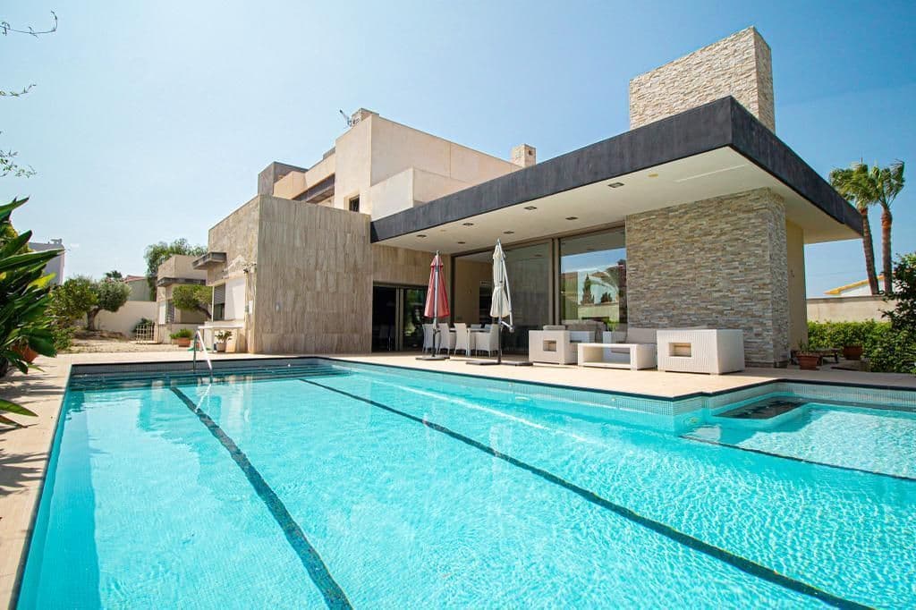 Luxury villa 900 meters from the beach. The plot area is approximately 1250 square metres, of which 355 square metres are in the built-up area. The distribution of the house is as follows: On the main floor there is a master bedroom with a magnificent walk-in wardrobe and an en-suite bathroom with whirlpool bath. Then there is a spacious living room with large windows of 3 meters high, which provides maximum natural light. This living room is connected to the designer kitchen with a beautiful granite island in the middle for cooking comfort.  The kitchen also has access to a swimming pool of 61 metros with jacuzzi and waterfalls. Adjacent to the kitchen is a laundry room connected by a pipe to the upper floor for the convenience of transporting laundry. Completing this floor is a guest bathroom and a room that can be used as an office. On the first floor there are four bedrooms, each with its own bathroom and a separate terrace. The first floor offers a terrace with panoramic views of the city, the sea and the mountains. As for the quality of the finishings, the floor is made of high quality porcelain stoneware and has underfloor heating. The windows are made of triple glazing, providing thermal and acoustic insulation. In addition to all this, the property is equipped with central air conditioning for hot and cold, and there is the possibility of installing a lift according to the floor plan. And finally, there is a magnificent garage of approximately 350 square metres and ceiling height 5 meters for 12 cars with an anti-seismic structure.
