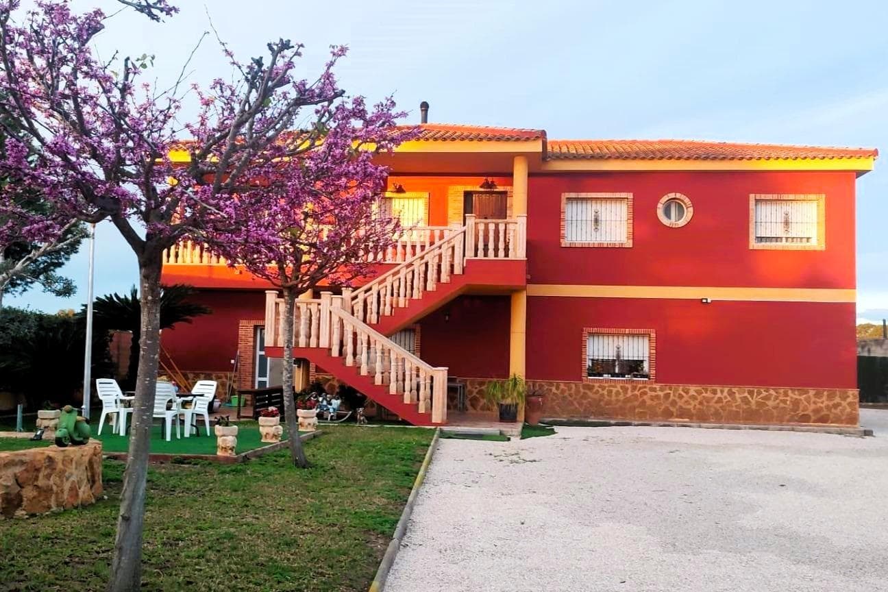 MAGNIFICENT VILLA (253 m2 – 1,200 m2 PLOT) WITH 5 BEDROOMS, 3 BATHROOMS, TWO KITCHENS, LARGE LIVING ROOMS AND GARAGE. BUILT IN 2010 WITH THE HIGHEST QUALITY. APPROX. 3 KM FROM ORIHUELA CENTER AND SURROUNDED BY ORCHARDS. Surrounded by orchards and with views of the mountains is this magnificent villa, built in 2010, with 5 bedrooms, 3 bathrooms, and large living areas. The house is furnished with two complete kitchens and can be used as two separate homes. On the large plot, where there is plenty of space to build a large swimming pool, there is also a large separate storage building (approx. 40 m2). Perfect for those looking for a quiet place to live outside the city, for multi-generational living, or running a business where you need space! KEY FEATURES: –Quiet surroundings with orchards and mountain views. –Upstairs: Large living room with fireplace, lounge with pool table, large separate kitchen with dining area, 3 bedrooms, 2 bathrooms, and a large terrace with wonderful views. –Ground floor: Living room with dining area and open kitchen, 2 bedrooms, 1 bathroom, laundry room, storage rooms. large garage and terrace in front of the entrance. –1,200 m2 plot – plenty of space to build a large swimming pool. OTHER ADVANTAGES: –Separate storage building (approx. 40 m2). –Several modern ACs (air source heat pumps). –Solar panels on the roof of the storage room. –Strategic location near the A7 and only 20 km to Murcia and 30 km to Torrevieja. The house was built in 2010 with consistently high quality in both construction and materials. It is in very good condition, ready to move into immediately! By car you can reach Murcia and Torreveja in 30 minutes, and located only 500 m to the Miguel Hernandez University in Desamparados, there is also functioning public transport, despite the rural location. Don't miss out on this magnificent villa, perfect for the large family, for multi-generational living, or for those who also need space to run a business! Contact us today to book a viewing. Write to us and you will be put in touch with a team member who speaks your language!