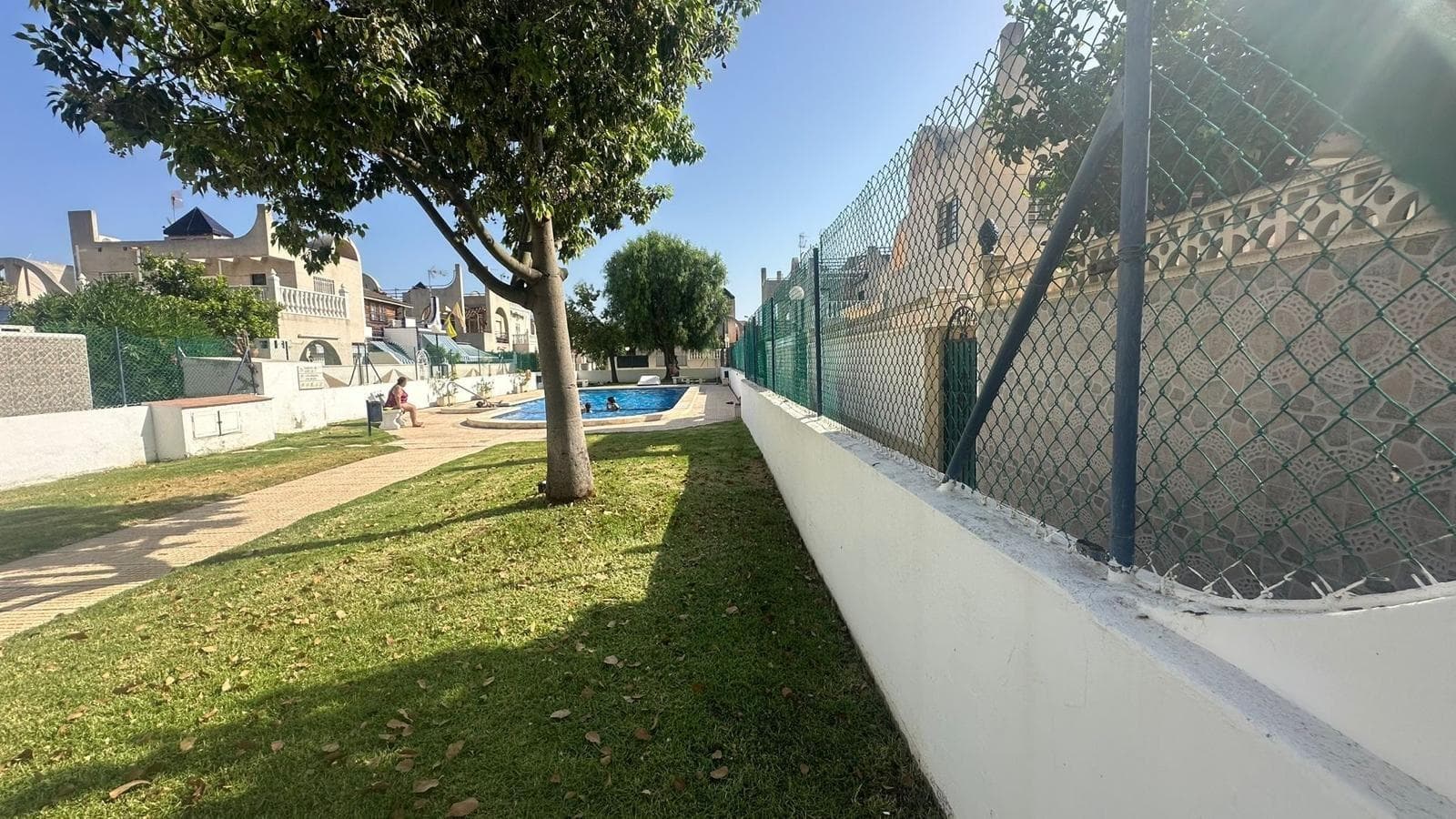 Charming Townhouse with Private Solarium and Communal Pool in Doña Inés Urbanization – Torrevieja We present this fantastic townhouse located in the exclusive and quiet Doña Inés Urbanization, one of the most desirable areas of Torrevieja, ideal for those looking to live in a safe, peaceful environment with all amenities just minutes away. The property has 80 m² of built area and stands out for its excellent layout and spacious outdoor space. A cozy private garden surrounds the home, perfect for enjoying al fresco meals, creating a chill-out area, or simply relaxing in the sun. It also has a storage room, ideal for additional storage. Upon entering the home, we find a very bright living-dining room with a perfectly integrated open-plan kitchen, offering a modern, practical, and functional space. On this same floor, there is a full bathroom with a shower and a double bedroom, ideal as a guest bedroom, office, or master bedroom on the ground floor. Going up to the second floor, we find a single bedroom, another full bathroom with a shower, and the master bedroom, which stands out for its spaciousness and direct access to a beautiful terrace overlooking the communal pool, a perfect space to relax and enjoy the surroundings. As a finishing touch, the property features a private solarium on the upper floor, ideal for sunbathing, hosting barbecues, or enjoying quiet moments with unobstructed views. The Doña Inés development offers its residents a communal pool, perfect for cooling off on summer days and enjoying a relaxed, family-friendly atmosphere. An ideal opportunity for those looking for a ready-to-move-in home with spacious outdoor spaces, a private solarium, and a communal pool, located in one of the most sought-after areas of Torrevieja.