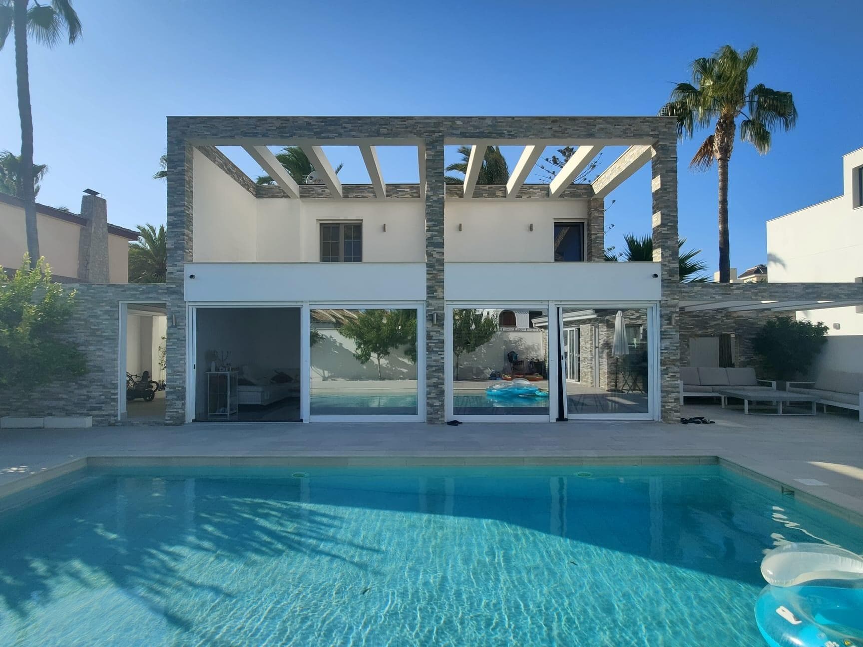 This spectacular villa is located in the prestigious area of La Zenia, Orihuela Costa. With a surface area of 240 square metres distributed over a plot of 600 square metres, this property offers a spacious and luxurious living space. The villa has 4 double bedrooms and 3 bathrooms, perfect for accommodating the whole family and entertaining guests in comfort. This pre-owned property is presented in excellent condition, ready to move in and start enjoying a quality lifestyle. Among its outstanding features are the following extras: -Water, electricity and air conditioning. Built-in wardrobes in the bedrooms, providing ample storage space. -A beautiful garden surrounding the property, creating an atmosphere of peace and tranquillity. -The property is very bright, with large windows that allow natural light to enter. -Private patio for al fresco dining. -An impressive swimming pool of its own, perfect for cooling off on hot summer days. -A basement, ideal for use as a games room, gym or additional storage space. -Solarium with unobstructed views, where you can enjoy moments of relaxation and take in the panoramic views. -High ceilings that add elegance and spaciousness to the interior spaces. -Terrace to enjoy the views and the Mediterranean climate. -Storeroom for storing objects and utensils. -Storage space for several cars. The location of this villa is unbeatable, with access to buses and surrounded by trees, in a central area with easy access to shopping centres, medical centres, schools and supermarkets. It is also just minutes away from the coast and golf courses, as well as hospitals, parks, and other amenities. This villa offers an exclusive lifestyle in one of the most desirable areas of the Costa Blanca, with all amenities and services within easy reach. Don't miss the opportunity to purchase this unique property, contact us for more information or to schedule a viewing!