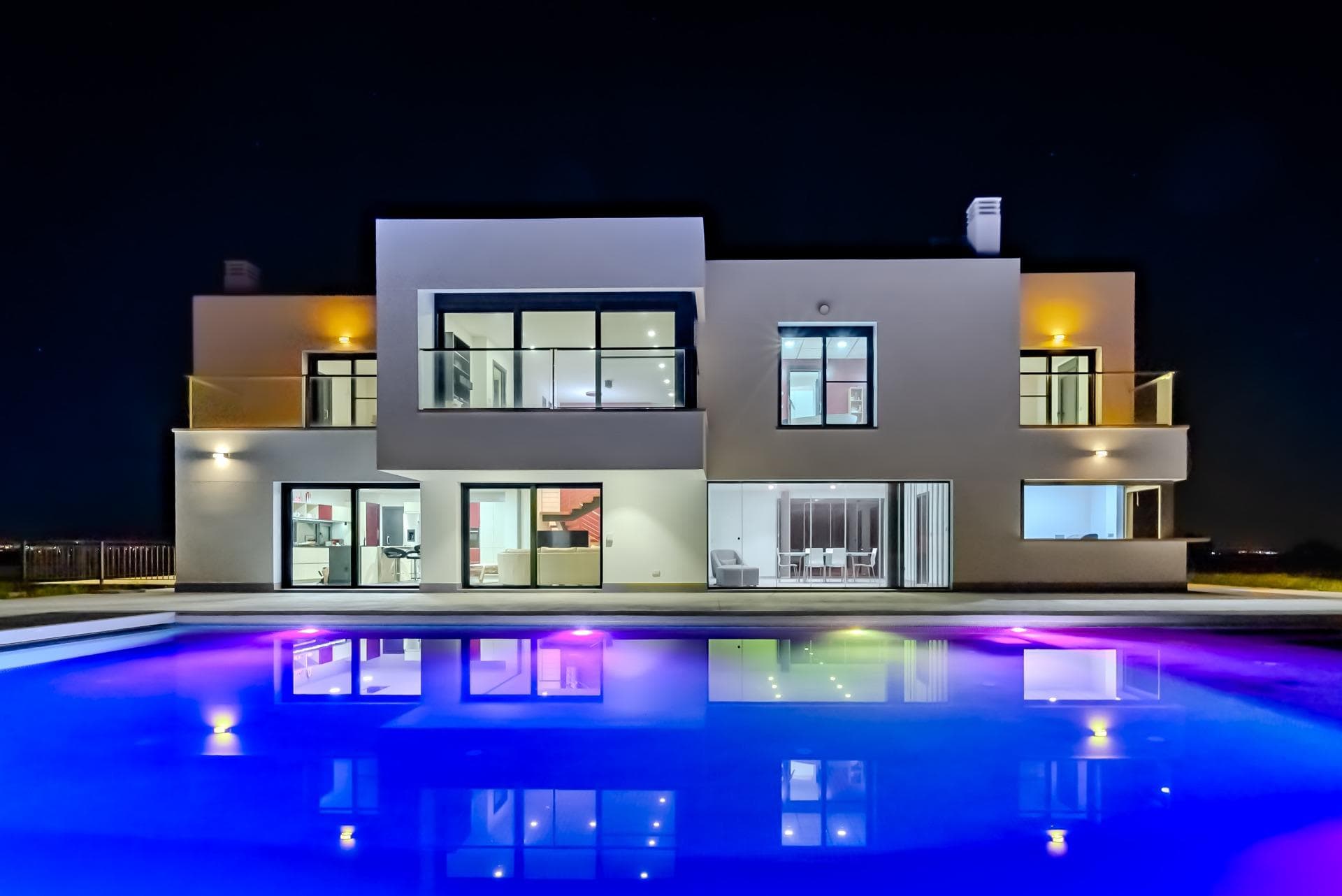 Nestled in La Marina del Pinet (Elche, southern Alicante), this stunning contemporary-style villa was built in 2016 on an expansive 10,600 m² plot, offering absolute tranquility and privacy. With optimal sun exposure throughout the day, it boasts 360° panoramic views of the countryside and surrounding mountains. Its strategic location ensures excellent connectivity: just 5 km from the beach, 3 km from La Marina village, 20 km from Elche and Torrevieja, and 25 km from Alicante Airport. 🏡 A home designed for limitless living and enjoyment. Built with top-quality materials and no detail spared, this exceptional property delivers superior levels of comfort, security, and functionality: Anti-theft security windows Electric blinds and mosquito screens throughout Premium appliances and designer kitchen Full accessibility: elevator from basement to first floor, ramps, wide and sliding doors 🌞 Natural light, open-plan design, and stunning views. The south-facing façade, which opens toward the pool, features expansive windows that fill the interior with natural light. On the main floor, a spacious fully equipped kitchen connects seamlessly to the open-concept living area. These spaces can be divided with elegant sliding glass doors for added versatility. The central island includes an induction cooktop and extends into a stylish table with seating for up to 12 guests. A laundry room with exterior access completes the space. From the living room, a large covered terrace is accessed through a retractable glass door. Accordion-style windows open completely to the north and south, creating a seamless indoor-outdoor experience. The terrace leads to a storage room, a summer kitchen with bar and indoor barbecue, and an outdoor bathroom. Also on this level is a guest bedroom with en-suite bathroom and a separate guest toilet. 🛏️ Private spaces designed for total relaxation. Upstairs—accessible via elevator or stairs—you’ll find a bright, open-plan room ideal as an office, games room, or gym. From here, enter the luxurious primary suite featuring a fireplace, private terrace, large walk-in closet, and an expansive bathroom with a central freestanding tub, oversized shower, double vanity, and separate toilet. Two additional bedrooms with en-suite bathrooms and private terraces are also located on this floor. 🚗 Multifunctional basement and dream garage. The basement level offers a versatile room with a private bathroom—perfect as a fifth bedroom, home office, cinema, or fitness room. The extra-large garage accommodates several cars, motorbikes, and bicycles, and houses the technical systems for the pool. 💦 A year-round private wellness retreat. The 12 x 6-meter pool includes a gradual beach-style entry, a deeper lap lane, and a UV purification system, allowing for nearly chlorine-free, healthy swimming. The elevated 3 x 3-meter jacuzzi, overlooking the pool, creates a serene, zen-like setting. A heat pump system ensures both the pool and jacuzzi can be enjoyed year-round. A solar-powered shower is located poolside. 🌱 Eco-efficiency and sustainability. The rainwater and greywater collection and recycling system is fully operational and used to irrigate the gardens, trees, and lawn—an eco-conscious solution that enhances comfort while respecting the environment. 📐 Property Layout: Main floor: 168.40 m² Upper floor: 125.55 m² Basement: 186.30 m² ✨ Are you ready to discover your future home? A modern, private, and fully functional paradise, just minutes from the sea. This is more than a property—it’s a lifestyle. Contact us today to schedule your private visit. Your dream home is waiting!