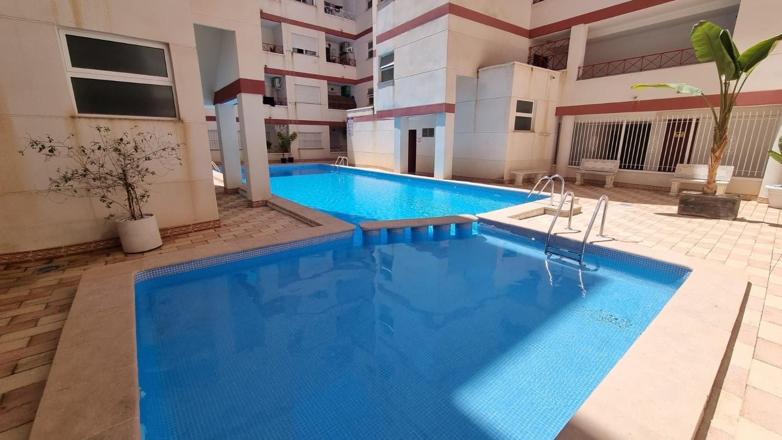 This exclusive fully renovated apartment is located on the second floor in the sought-after Parque de las Naciones area of Torrevieja. East-facing, the property enjoys plenty of natural light and premium, modern finishes throughout. It features two bright bedrooms, the main one with a built-in wardrobe, a stylish full bathroom, and an open-plan American kitchen equipped with the latest appliances. The spacious living-dining room opens directly onto a private terrace, perfect for breakfasts or relaxing outdoors. There is also an independent gallery utility area. The apartment comes fully furnished, with wood-effect floors, double-glazed windows, and contemporary décor. The building offers a community pool and lift, ensuring extra comfort and a friendly atmosphere. Superb location just steps from the beautiful Parque de las Naciones, surrounded by all amenities—supermarkets, pharmacies, schools, public transport—and only minutes from Torrevieja’s best beaches. Ideal as a year-round residence or as an excellent investment for holiday rentals.