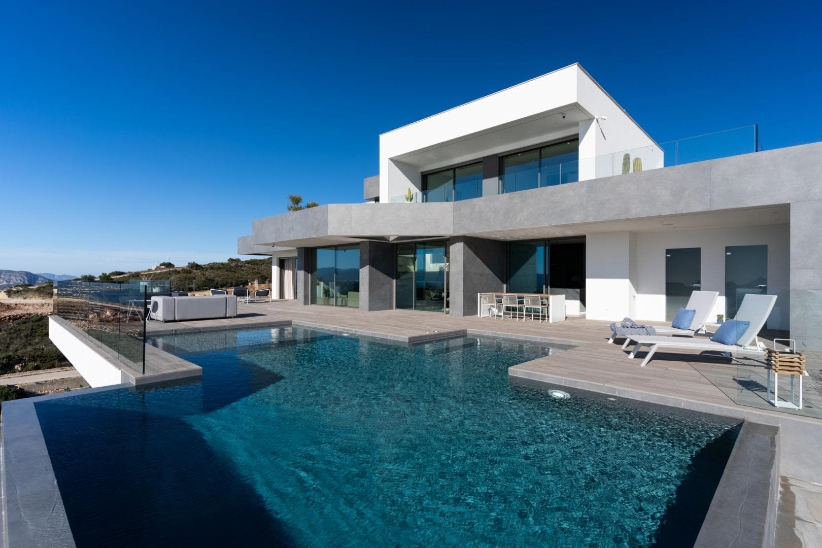 NEW BUILD LUXURY VILLA IN CUMBRE DEL SOL

New Build iconic villa in Benitachell. Its design from the 21st century blends in with the exclusive surroundings of Residential Resort Cumbre del Sol perfectly. It is built on a 1168m2 plot of land, where, as the villa faces the southwest you can see and enjoy amazing sunsets.

Everything about this villa shouts out quality and style, with an intelligent design that offers a practical distribution of the villa that optimises, even more, its exceptional views of the Mediterranean.

A home with many spaces to enjoy lounging around and family life in front of the sea. There are several rooms all connected with each other to be able to live different moments of the day in different settings. A dining room and living room, a kitchen with a central island where you could enjoy a perfect breakfast, and a large summer porch with a BBQ. All these rooms are laid out so you can enjoy good conversation, celebrate important family events or for you to just relax gazing at the sea

The main bedroom was designed thinking about comfort and relaxation. It is a private area with a large en suite bathroom with bath and shower facing the sea. It also has a large walk-in-closet and access to a private terrace.

Cumbre del Sol is located in Benitachell in the heart of the mountain of la Llorenca, north of the Costa Blanca. It lies between the two coastal towns of Javea and Moraira and it´s surrounded by exceptional protected areas such as the Natural Park of La Granadella. It´s very close to wonderful beaches and coves and cities like Denia, Calpe and Altea.
Whether you enjoy a couple of days, a holiday, a season, or the full year in our luxury resort in Benitachell, you'll find that Cumbre del Sol meets your every expectation.
Golfers, divers, nature-lovers, and sun-seekers are just minutes from the dozens of heavenly destinations on the Costa Blanca that surround our development.
