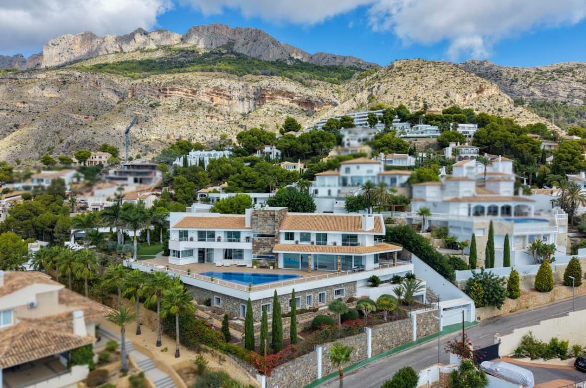 This stunning villa is a work of modern architectural art set in the prestigious Sierra de Altea, one of the most exclusive residential areas on Spain’s Costa Blanca. The property sits on a generous 2,035 m2 plot and offers an impressive 1,605 m2 of covered living space distributed across three levels, all served by an elevator, with additional underground parking for six vehicles. Designed to combine Mediterranean charm with clean, contemporary lines, the villa embodies refined elegance, functionality, and ultimate comfort.From its privileged location, the villa enjoys a complete 360-degree panorama that takes in the Mediterranean Sea to the south and the rugged Sierra Bernia mountains to the north. On clear days, the islands of Ibiza and Formentera appear on the horizon. Despite its tranquil setting, the property lies only a short distance from Altea’s historic centre, the sandy beaches and marina, as well as golf and tennis clubs, all within a few minutes’ reach.The main living spaces are conceived for both grand entertaining and intimate family life. Expansive lounges, dining areas and a state-of-the-art Italian designer kitchen with a central island open seamlessly onto wide terraces of more than 370 m2. The sense of space is enhanced by floor-to-ceiling windows that flood the interiors with light and frame the spectacular sea views. The villa houses a total of seven bedrooms and six en suite bathrooms + guest toilet and separate bathroom, offering plenty of space for family and guests. Each guest suite is individually designed with comfort and privacy in mind, while the opulent master suite takes up the entire east wing of the first floor. This private haven features vast windows, a bioethanol fireplace, two terraces overlooking the Mediterranean, a sumptuous bathroom with soaking tub and glass shower, and an expansive walk-in dressing area.The lower level of the villa is dedicated to leisure and wellness. The recreation floor of over 500 m2 is prepared to include a cinema area, billiards, a playroom, a fully equipped gym, a massage room, a lounge and relaxation room and a spa with sauna, hammam and a salt cave. Currently only a gym is installed but the plans show the possibility of converting this floor in a true leisure paradise. Below, the basement level houses the garage for six cars, motorcycle bays, storage rooms and the technical installations of the property.Throughout the villa, only the highest quality materials and finishes have been selected. Handpicked marbles, exotic granites and fine woods create a unique atmosphere of sophistication. Equipment includes Daikin air-conditioning and heating pumps, underfloor heating, high-speed fibre optic internet, video surveillance and alarm systems, as well as home automation that can be remotely controlled from any device. Double-glazed windows with automatic shutters, Italian parquet and ceramics, designer lighting and bespoke kitchens from Dada Molteni/Armani and Schüller fitted with premium Miele and Bosch appliances reflect a standard of absolute luxury.The outdoor spaces are equally impressive. A wooden deck leads to the infinity pool, framed by a perfectly maintained subtropical garden with jasmine, bougainvillea, wild roses, rare fruit trees and elegant palms. An automated irrigation system, eco-friendly lighting and robotic lawn care ensure effortless maintenance. A 400 m2 central lawn integrates a meditation zone, a barbecue area and the pool terrace, offering multiple ambiences to enjoy the Mediterranean lifestyle all year round.This unique villa is more than a residence; it is an exceptional estate conceived for those who value privacy, design excellence and the highest levels of comfort. With its commanding views, innovative architecture and luxurious details, this property represents one of the finest offerings currently available on the Costa Blanca.