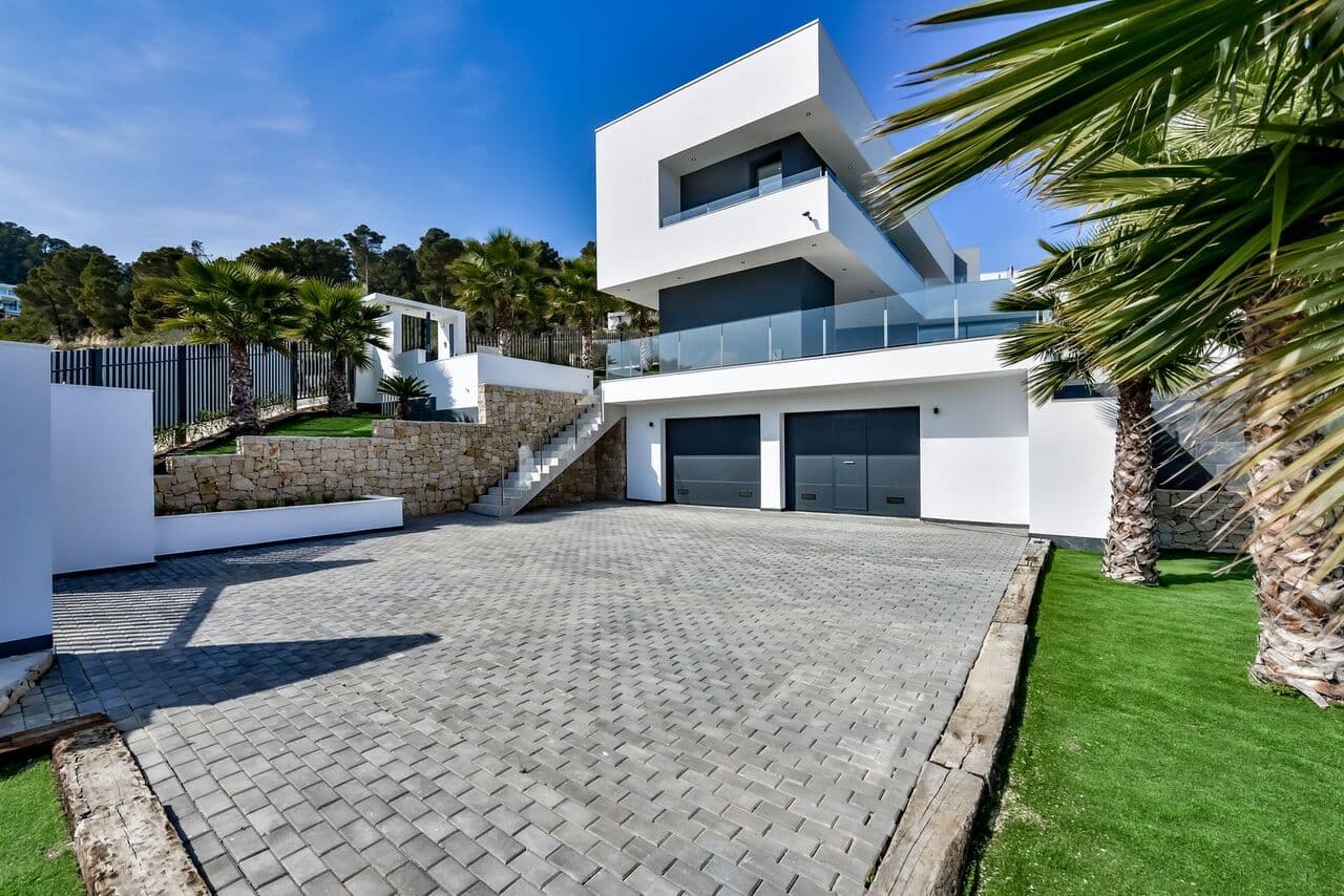 Ready to move into - a modern luxury villa in a prime location with sea views - Urb. Tosalet 5, Javea The property offers an open view of the green hills up to the sea. On a clear day you can look out over the Mediterranean to Ibiza. Modern architecture with clean forms and straight lines, exciting combination of classic elements and avant-garde materials make the hearts of architecture fans beat faster. In the basement there is a double garage with automatic door and a spacious basement area. The ground floor is divided into a large living - dining area, kitchen with adjoining utility room and a guest toilet. A large covered terrace with BBQ - area offers a shady place in the summer months, from here you can enjoy lovely sea views. The open pool terrace with a large pool, with infinity effect, wide entry steps and underwater lights. Upstairs there are 3 spacious bedrooms and 2 bathrooms. The master bedroom has a bathroom en suite. All bedrooms have access onto the large roof terrace. Kitchen: The villa comes fully equipped with a fitted kitchen, ceramic hob, oven, microwave, dishwasher and high-quality built-in furniture. Heating - Hot water: Heating is provided by a air heat pump with support of solar energy. Air conditioning: Installed central air conditioning system, which distributes the cooled air to the different areas of the building. Garden: The garden is terraced by stone walls, the individual terraces are planted with local plants. Irrigation via a central irrigation system. Plot hedging: The plot is completely enclosed by walls and fences. Driveway to the garage with an electric gate, another access from the street on the front door level.