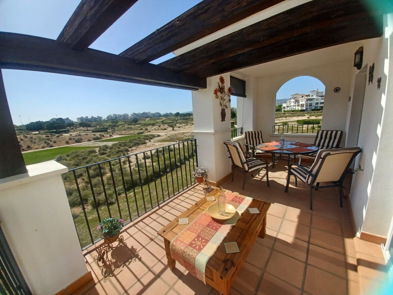 This light, bright and airy apartment situated on Calle Indico in Hacienda Riquelme Golf Resort really has it all; beautiful panoramic views of golf and lakes, South facing terrace part open and part closed with is sunny all day long, fully furnished and ready to move in.  The apartment enters into a hallway leading to a spacious living room with sofa, armchairs and unit with TV and airconditioning.   The living area has patio doors to lead to the terrace, the terrace has open space for sunbathing and covered area for dining whilst looking at the spectacular views.  There are 2 bedrooms, the main bedroom has patio doors and leads to the terrace, it is furnished with twin beds and fitted wardrobes.  The second bedroom is also a double with ceiling fan, fitted wardrobe and views to the garden.  The bathroom has been upgraded with a walk in shower and it has a window.  The kitchen is well maintained and comes with a fitted kitchen, oven, hob, extractor, fridge freezer; there is a separate untlity room with washing machine and gas boiler.  The apartment comes with underground parking space and in a community with 19 pools, gardens, 24 hour security, sport facilities (outdoor gym, tennis, padel) WIFI and satelite TV.  The resort has restaurant and supermarket just a few minutes walk, situated just 5 minutes drive to Sucina village,  20 minutes from Corvera Airport and 20 minutes to the beach, this apartment has so much to offer, it is highly recommended.