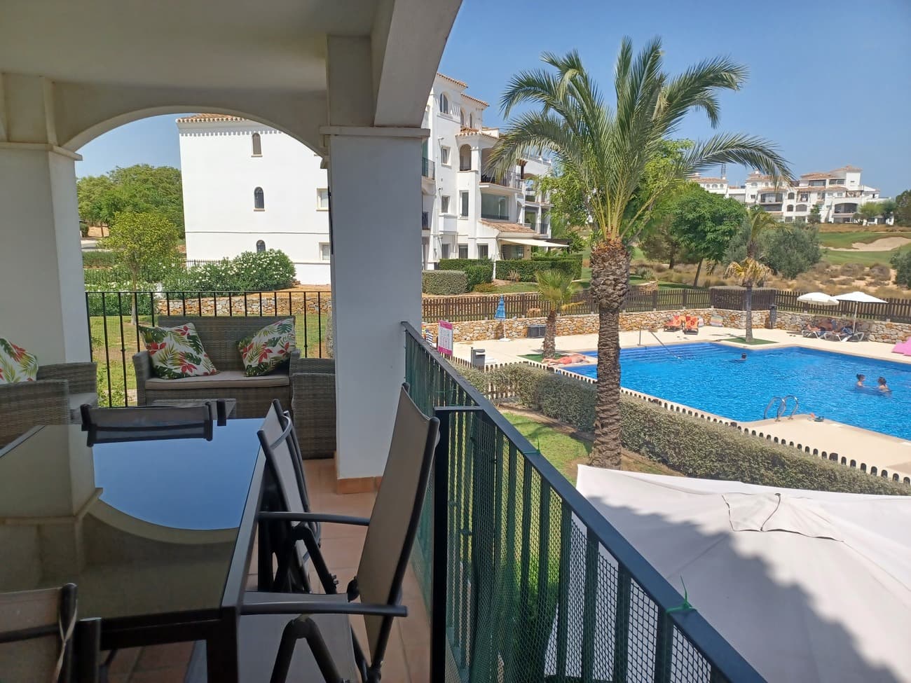 Situation on the first floor this beautiful corner apartment is light, bright and airy. It offers spectacular views over the pool and the golf course.  The apartment  enters into a spacious living/dining room well furnished with sofa, dining table and chairs, units and TV with patio doors and windows allowing plenty of natural light and views.  The living room leads to a spacious terrace, it is a long covered terrace with arches with plenty of space for outdoor living and dining and enjoying the sunshine.  The living room leads to a hallway; to the left is the kitchen, with a fitted kitchen and well equipped with high quality electro domestics; ceramic hob, oven and canopy; washing machine, fridge & freezer.  The bathroom is very spacious and it has been upgraded, it has a large walk in shower, vanity unit, wc and bidet and it comes with an arched window.  There are two double bedrooms at the rear of the apartment, both come with patio doors leading to a balcony and views over the gardens.  Both bedrooms are with fitted wardrobes, double beds and bedside cabinets and ceiling fans.  The apartment comes with lift and underground parking space and this apartment is also situated close to the entrance gate and just a short walk to the ´town centre´ with restaurant, cafe and supermarket.  Situated in Hacienda Riquelme Golf Resort the community includes 24 hour security, gardens, 19 pools, sports facilities, WIFI & satellite tv offering high standard living.  This apartment is highly recommended for viewing.