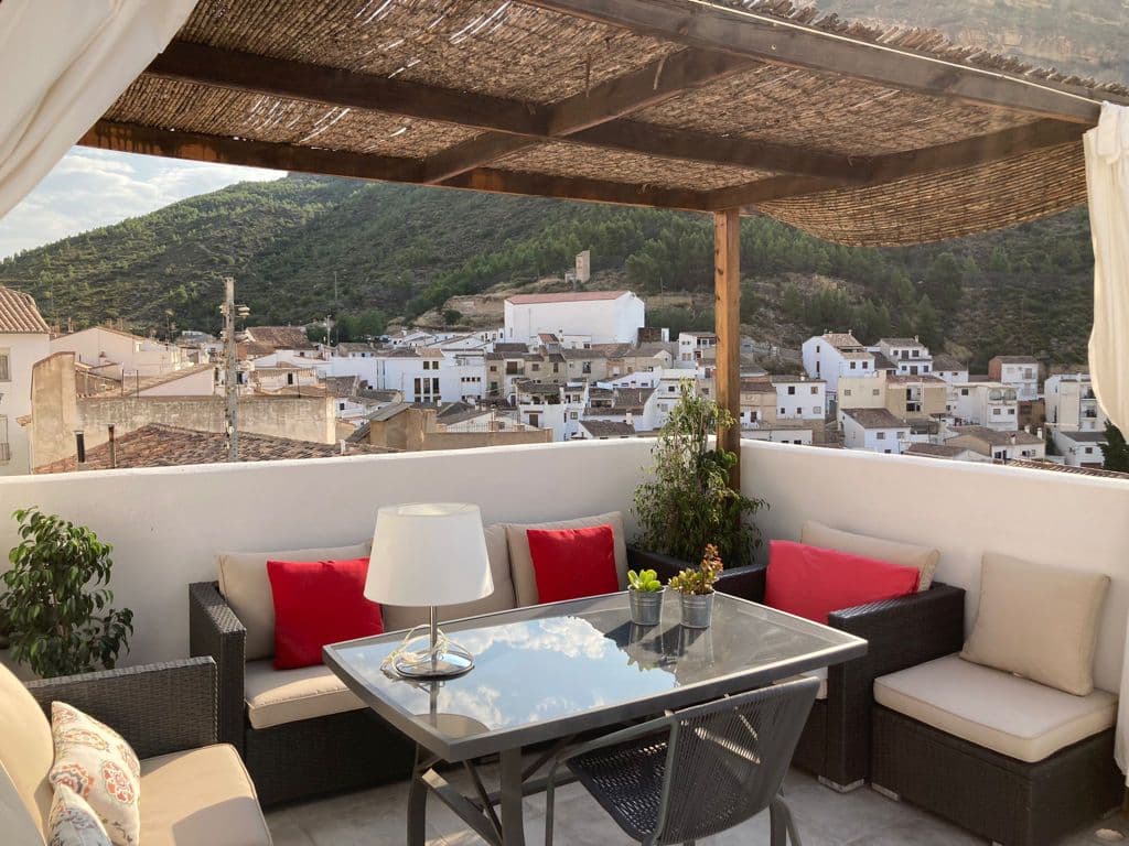 Unique 4-bedroom, 2-bathroom townhouse, located in the heart of the world-famous hiking and rock-climbing town of Chulilla, Valencia.This townhouse is set over three floors and comprises two separate accommodations, each with their own entrance. As we enter the property through the main door, we find what is the primary house, consisting of a large entrance hall, living room and guest toilet. Steps from here take us to the kitchen/dining room, complete with log burner and chimney. On the next floor, we have three double bedrooms, one of which has access to a small Juliette style balcony which overlooks the cobbled pavements and whitewashed houses in the street below. On this floor there is also a family bathroom, with a shower.Steps to the final floor take us to the complete independent one-bedroom apartment, which has its own entrance via a street to the rear of the property. Here we have an open-plan living room, again with a log burner and chimney and a small kitchenette with dining space. There is another double bedroom, that boasts an en-suite bathroom with a shower. Finally, on the rooftop, we find the fantastic 18m² terrace which has incredible views of the village, its castle and valley below. Just imagine enjoying your morning coffee with these breath-taking views as your backdrop every day. The property has been decorated with great style and attention to detail, with all furniture being included in sale price.This property has been a working business for the past six years and generates a great revenue per year. It already has the tourist licence needed to operate as a running holiday home and can be found on commercial portals. As the property is divided into two different living spaces that can be made completely independent of eachother, you have the option to live onsite whilst renting out the rest of the property. Chulilla is a tourist destination, located in Los Calderones national park, renowned globally for its hiking and rock-climbing trails, as well as kayaking at the local waterfalls and nearby reservoir. The village itself has all necessary amenities such as shops, schools, bars and restaurants. Valencia city centre, with its beaches, airport and historical old town can be found an hour´s drive away (70km).