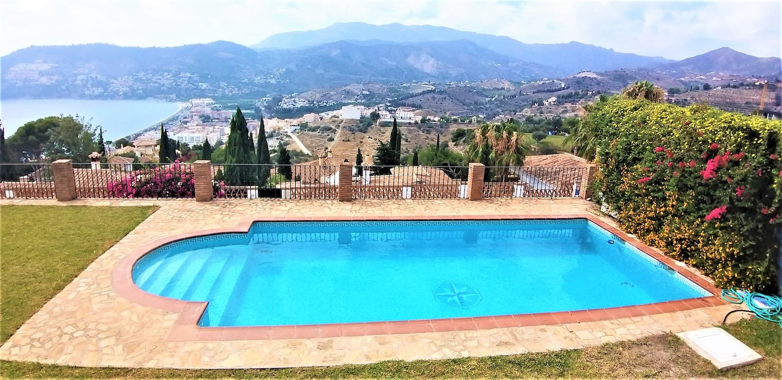 Fantastic Offer! Price Reduced from 1,800,000€ to 1,650,000€Discover this luxurious and elegant pool villa for sale in the exclusive urbanization Punta de la Mona, La Herradura, on the Costa Tropical. This spacious home offers five bedrooms with en-suite bathrooms and an additional guest bathroom. The well-planned garden spans over a plot of more than 800 sqm. Perfectly located, just an hour's drive to Malaga Airport and a 20-minute walk to the nearest beach.The entrance to the house impresses with a magnificent Sevillian courtyard, adorned with colorful potted plants, artisan tiles, and a beautifully paved terrace. A large solid wood door welcomes you into a spacious hall that connects the different parts of the house. To the right, you find a large fully equipped kitchen, which leads to a bright and spacious living room.From the living room, you step out onto the house's gem, a large covered terrace with wonderful views of the Alboran Sea and the mountains of Cerro Gordo. The surrounding garden with its lush lawn and refreshing pool is the perfect place for sunbathing and cooling off on hot days, as well as for relaxing with family and friends in the evening. The terrace is beautifully decorated with authentic pillars.From the living room, you reach the bedrooms, and to the left of the hall, from the entrance, is a spacious corridor decorated with elegant lamps, leading to three large bedrooms with en-suite bathrooms. There is also a fourth, beautifully decorated guest bathroom.At the top of the house, you find a cozy TV room and a space for relaxing with a good book, which also leads to a sun terrace with the best view of La Herradura and the Mediterranean.The elegant oak staircase leads down to the basement, which covers nearly 300 sqm and includes two bedrooms with en-suite bathrooms, a laundry room, a pantry for food storage, and a very large garage with space for multiple vehicles. Here is also the boiler room with the climate system that controls the house's central air conditioning and underfloor heating.In summary, this is a magnificent house in Andalusian style with Sevillian inspiration, located in a beautiful enclave on the Costa Tropical by the Mediterranean. Surrounded by a well-maintained garden and with spectacular views of the Alboran Sea and the mountains of Cerro Gordo. Built with care and heart, this house is a true gem that must be experienced. The house is sold with essential furniture specified during viewing, while other furniture and personal items can be removed by agreement.Welcome to your dream home on the Costa Tropical!