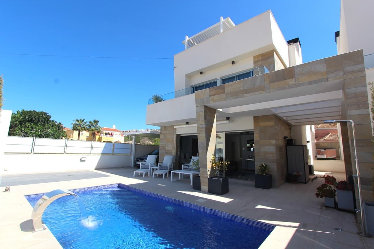 Completed in 2022, this fabulous 3 bed (potentially 5), 4 bath contemporary style new-build villa is the finest example of the Don Benito style villas, incorporating every conceivable ‘extra’ and the very highest specification.  Conveniently located in the El Galan urbanisation nr Villamartin and close to all amenities and numerous golf courses, it’s situated only a few minutes to both the Villamartin Plaza and La Fuente Commercial Centre as well as being less than a 7 minute drive from the fabulous La Zenia Boulevard and those amazing Costa Blanca beaches!Internally, this incredible property comprises two stories with an additional under-build and rooftop solarium, all of which benefit from hot/cold air conditioning.  On the ground floor you will find one of the three double bedrooms together with a full family bathroom including shower. There is a spacious open-plan kitchen and dining area incorporating a well appointed modern kitchen equipped with all of the modern facilities you would expect and giving access out to the covered utility and storage area which also houses a washing machine.  The lounge area enjoys full height, double-glazed sliding doors along the length of the external wall giving direct access out onto the sun drenched covered terrace area and large 6x3m private swimming pool.  Fully tiled and privacy screened, the outside area offers usable space around the entirety of the property and incorporates a useful utility area to the rear as well as a covered car parking space and driveway to the left of the villa.  This outside space is what Spanish living is all about – sunshine, socialising and relaxing with a fantastic pool (with outdoor shower) to take a dip in when the sunshine gets too much!Stairs lead to the first floor accommodation which features two double bedrooms both of which benefit from their own en-suite bathrooms, fitted wardrobes and retractable insect window screens.  The master bedroom also offers access via glazed sliding doors onto a private balcony – the perfect spot to enjoy your morning cafe au lait.  A second internal stairway leads to the amazing private rooftop solarium complete with aluminium pergola for shade, a BBQ area also complete with pergola and a handy shower area.  This privileged spot offers the perfect relaxation and entertaining space with views across the parkland – as well as guaranteeing the perfect year round sunbathing spot.In addition to the superb internal and outdoor living accommodation, this fantastic villa also benefits from an incredible 56 sqm under-build which was a built as part of the original construction as a developer ‘extra’.  This incredible space is fully finished and comes complete with a fully fitted bathroom.  Currently being used as a workshop and a music & cinema room, this space offers the flexibility to be used as additional self-contained guest accommodation and would easily provide two further bedrooms in addition to the existing three, potentially making this a five bedroom, four bathroom luxury home…….  Or you could just leave it as every husbands (and wife’s!) dream ‘Man Cave’!Location, quality and value combine to make this property a truly exceptional prospect for anyone seeking the ultimate villa with easy access to all that the Costa Blanca has to offer – walking distance to the best bars, restaurants and shopping and only a few minutes drive from the Mediterranean and  those golden beaches – what more could you want?The property comes part furnished with most items included as shown.  