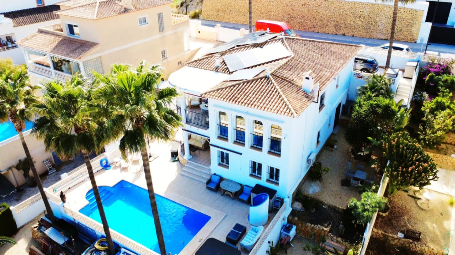 Located in the sought-after area of Bello Horizonte in La Nucia, just outside Altea, this charming family villa is the perfect place to live all year round. The property is distributed over two floors. The main access leads to a large integrated garage and a sunny porch, from which steps lead down to the garden, where you will find orange trees, mature lemon trees and beautiful palm trees.On the entrance level is the master bedroom with en-suite bathroom, a guest toilet, a spacious kitchen, a separate laundry room, and a large living-dining room with fireplace, air conditioning and central heating. Large windows offer spectacular views of the sea, covering Altea, Albir and Calpe. Next to the living room, a stunning terrace with panoramic views becomes the perfect place to enjoy a glass of wine while watching the sunset.The ground floor is accessible from both the inside and the outside, making it an ideal choice for entertaining. This area also has a separate kitchen, as well as 4 more bedrooms (one of them currently fitted out as an art studio), 2 spacious bathrooms and a beautiful terrace overlooking the heated pool area. The low-maintenance gardens, with palm trees, fruit trees and shrubs, create a relaxing atmosphere. The pool is the perfect place to cool off during warm, mild summer nights, and has the added bonus of a poolside Jacuzzi and an outdoor shower.The villa is equipped with solar panels, a battery, a heat pump and an aerothermal energy. Which makes this villa very energy efficient.