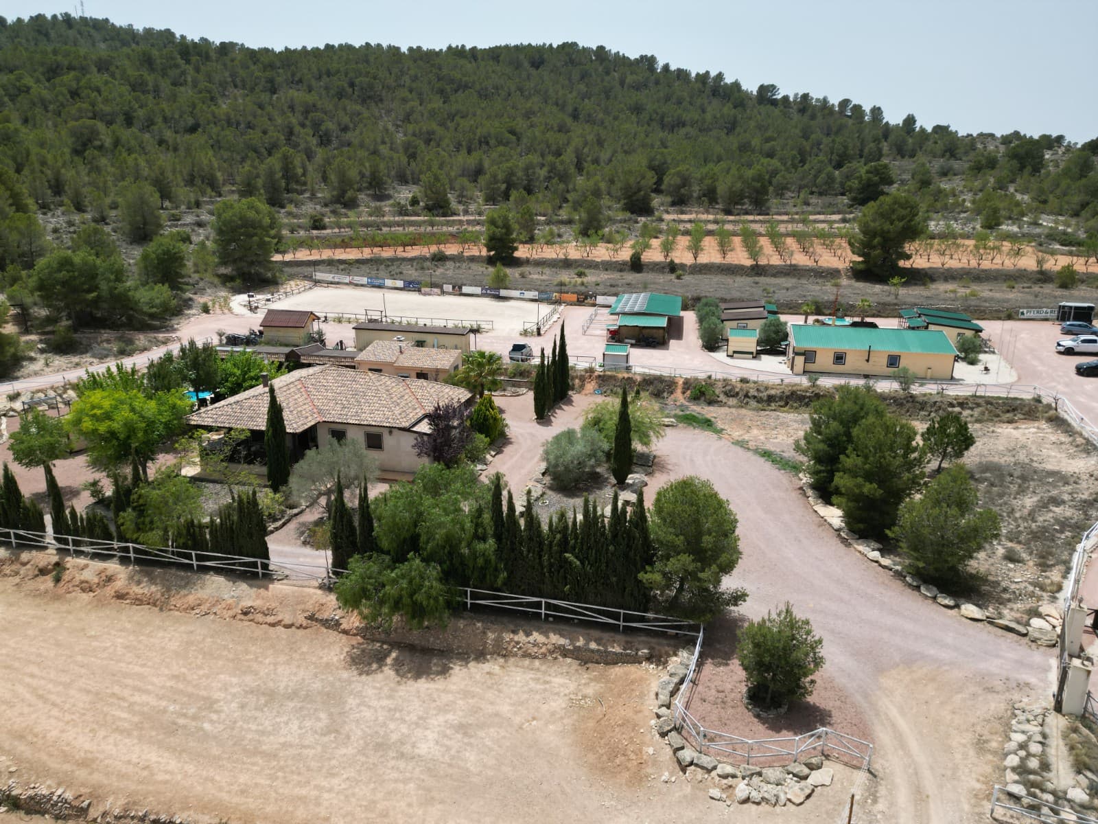 Exclusive Equestrian Estate with Private Residence in the Mountains of AlicanteLocated just five minutes from the town of Monòvar, this remarkable 3.7-hectare estate offers an exceptional opportunity for private living combined with professional equestrian facilities. Set in a peaceful landscape of pine forests, vineyards, and olive groves, the property boasts panoramic views of a picturesque valley, with the coast and Alicante Airport only 35 minutes away.The property is divided into two main areas: a private residential area and a professional equestrian centre, and the entire complex has been thoughtfully designed with well-kept paths, gravelled areas, white wooden fences and a variety of plants. A time-controlled irrigation system takes care of the green areas.Private living area: Main house with 165 m² of living space, single-level, ceiling height 3.5m 4 bedrooms, 3 bathrooms, kitchen, living room Central heating (oil), air conditioning Thermoglazed wooden tilt-and-turn windows with shutters and fly screens 2 sun terraces, a jacuzzi Partial basement (height 1.30 m) Sandstone facadePrivate Pool area: Illuminated pool with integrated filter system 85 m² covered chill area with fireplace Barbecue area with bar Outdoor kitchen Outdoor toilet and storage room Outbuilding for oil heating and tankEquestrian centre: Saloon building (approx. 150 m²) with outdoor terrace, bar, fitted kitchen and utility room Outdoor toilets 4 airconditioned guest houses with private terrace and shower roomPool area with sun loungers Stable building with 8 horse boxes (4x3 m each), 4 of which have outdoor paddocks Hay storage, Feed room Illuminated sand riding arena (20x40 m) Workshop and storage container with canopy and saddling area Fully insulated tack room 4 large group paddocks with automatic drinking troughs and electric fencing Separate living area for staffThe property has mains electricity supply, a 20 kW solar system and water connections across the entire site, including the paddocks. A REGA licence is in place to keep up to 17 horses.This ranch combines functional equestrian facilities with comfortable living spaces, all set against a stunning natural backdrop. Ideal for hosting guests or running an equestrian business, this property is a rare find. Experience the tranquility and beauty of mountain living while enjoying top-notch amenities for both you and your horses. About the Area:Monòvar is a charming town in the province of Alicante, known for its traditional Spanish character, wineries, and natural beauty. Surrounded by picturesque landscapes yet close to all amenities, Monòvar offers a peaceful rural lifestyle with easy access to Alicante's bustling city life, the airport, and the Mediterranean coastline. The area is ideal for nature lovers, horse enthusiasts, and those seeking a balance between privacy and convenience.