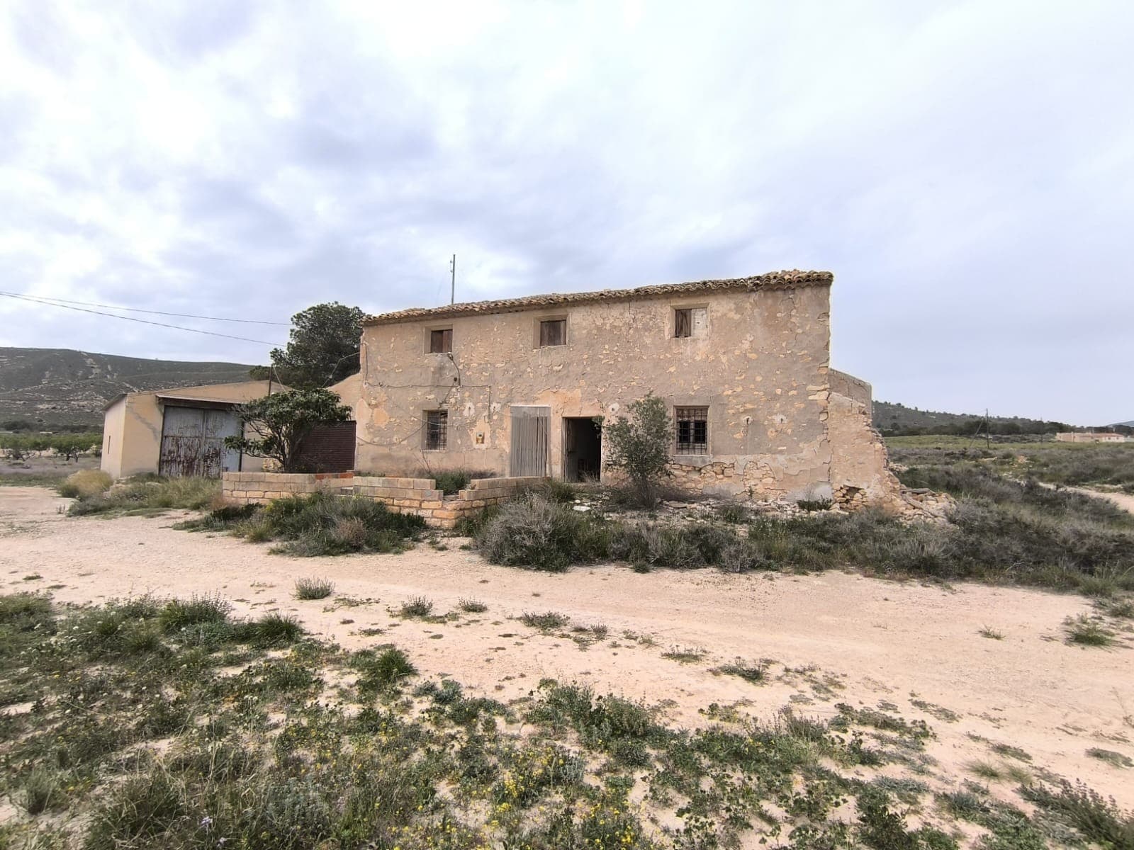 Discover a unique opportunity to own a restoration project nestled in the serene countryside of Jumilla. This property offers a blend of rustic charm and potential, perfect for those looking to create their dream home or investment. Situated 20 km from Jumilla and 18 km from Pinoso, this property is located in a remote, uninhabited hamlet, offering peace and tranquillity.Property Details:Old House (213 m²): This two-story house features 8 spacious bedrooms, a kitchen with a large fireplace, and high ceilings that add to its character and traditional Spanish style. Please note that the roof has collapsed in several areas and the house requires a complete restoration. An attached garage provides additional utility.Warehouse (155 m²): A solidly constructed warehouse in good condition, offering ample space for storage or potential conversion.Land (10,800 m²): Enjoy breathtaking mountain views from plot of land, perfect for gardening, farming, or simply enjoying the natural beauty of the area. The parcel has remnants of an old building.The property is connected to grid electricity and has access to both drinking and irrigation water, ensuring convenience for future development.This is a rare opportunity to invest in a property with immense potential in a picturesque setting. Don't miss out on the chance to bring this restoration project to life!About the area: Jumilla is a charming town renowned for its scenic vineyards, and vibrant local culture. Known primarily for its award-winning wines, this picturesque town offers a perfect blend of traditional Spanish character and modern living. With its historic landmarks, bustling market squares, and beautiful countryside, Jumilla provides an ideal setting for those seeking a peaceful yet vibrant lifestyle in province Murcia, 80 minutes from Costa Blanca.About us: We have a large portfolio of properties in the Costa Blanca and Costa Calida areas, specialising in country properties, villas, fincas, building plots and design and build options in the Alicante and Murcia regions with a particular emphasis on Elda, Monovar, Pinoso, Sax, Villena, Aspe, Fortuna, Albacete and many more surrounding areas. We have been established since 2004 and have decades of experience between the team which we bring to bear to help you find and secure your new dream home. We help you every step of the way to make sure your purchase in Spain is safe and hassle free. We are not here to sell you a property, we are here to help you realise your dream and find what is right for you. With us you are in the safest hands. Contact us now to have a no obligation chat about how you too can realise your dreams.