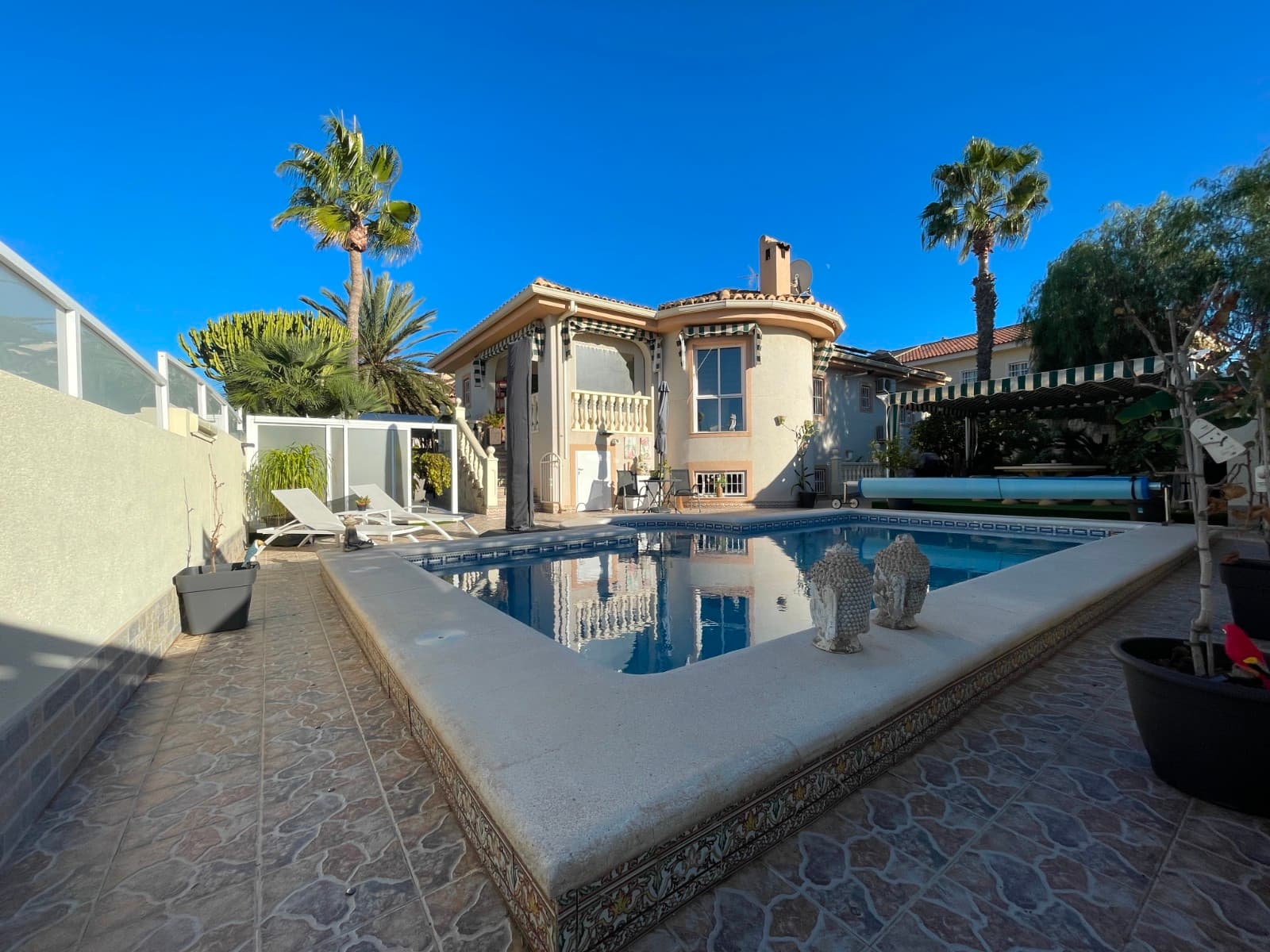 Charming Villa in Benijófar Located in a quiet and popular area between Rojales and Ciudad Quesada, this two-story villa sits on a 500 m² plot. The upper floor offers an entrance hall, living room, kitchen-dining area, two bedrooms, and two bathrooms (one en suite) with a cozy terrace. The lower floor includes an additional living room/bedroom, kitchen, three bedrooms, and a bathroom, making a total of 5 bedrooms.The property features a swimming pool, several patios, outdoor kitchen with dining area, garden, and parking space—perfect for families.The property features solar panels for energy efficiency, as well as a pool heating pump, perfect for enjoying the water all year round.Benijófar is an authentic Spanish village with all necessary services: restaurants, pharmacy, bank, and hairdresser, plus leisure options like golf and hiking trails. The beach and Torrevieja are only 15 minutes away by car.Perfect for those seeking a spacious, well-maintained home with a beautiful garden. Welcome to your new home.