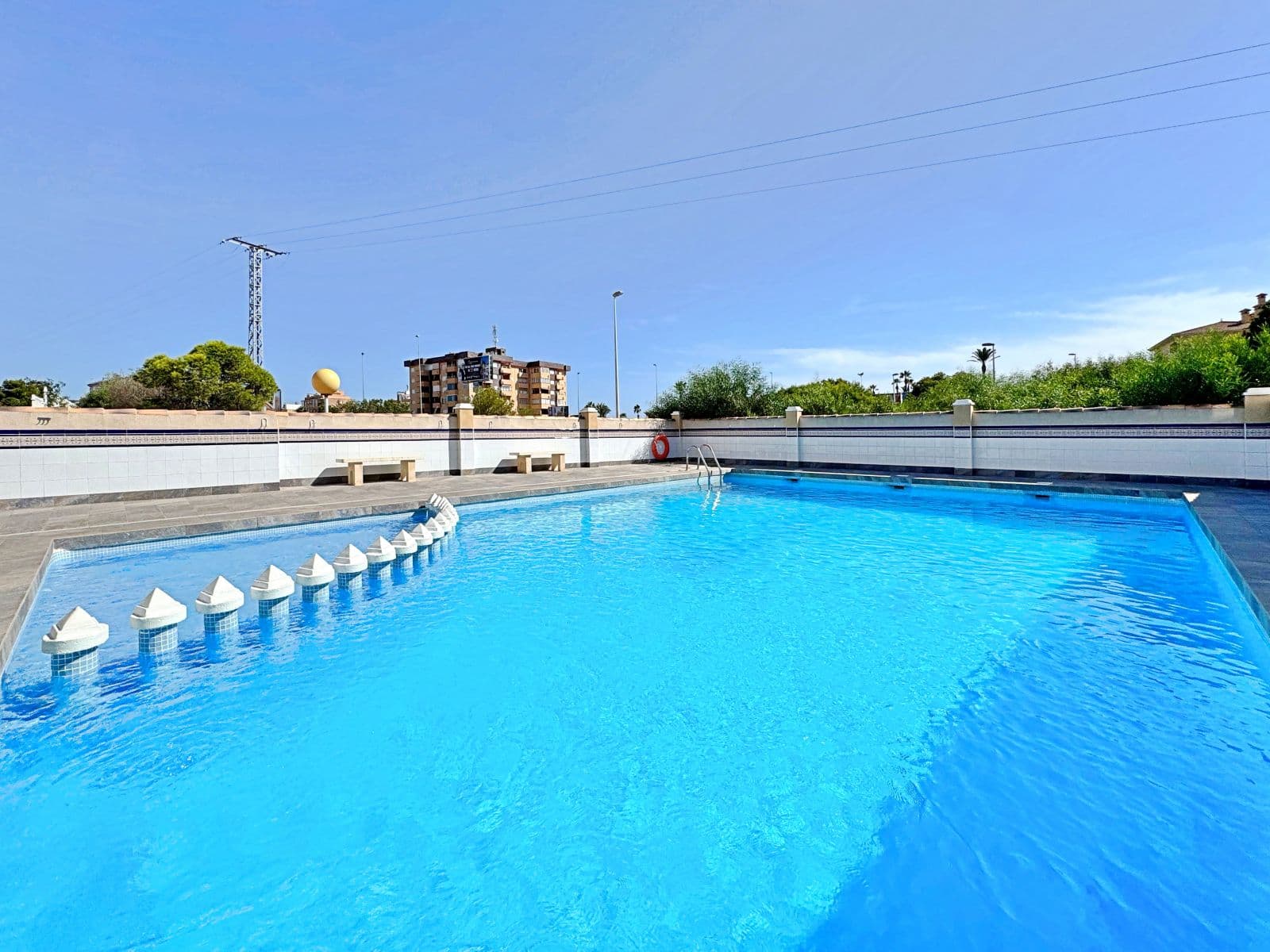 Located in the Zeniasol residential complex, just a short walk from La Zenia beach and the Zenia Boulevard shopping centre, this bright top-floor corner bungalow is in excellent condition.The property features a cosy living-dining room with a fully equipped open-plan kitchen, two double bedrooms with fitted wardrobes and a renovated bathroom with shower. Large windows provide plenty of natural light throughout, creating a warm and comfortable atmosphere.One of the highlights is the private solarium of approximately 40 m², perfect to enjoy the sun all year round. It includes a built-in barbecue and offers ample space to create relaxing areas, an outdoor dining space or even a chill-out zone with open views.The residential complex boasts a communal swimming pool surrounded by gardens, and the property also includes an exterior parking space.Its location is excellent: in a quiet setting yet within walking distance to all amenities such as supermarkets, restaurants, schools, public transport and leisure areas. Both the beach and Zenia Boulevard are only a few minutes away on foot.An ideal property either as a holiday home or as a rental investment in one of the most sought-after areas of Orihuela Costa.