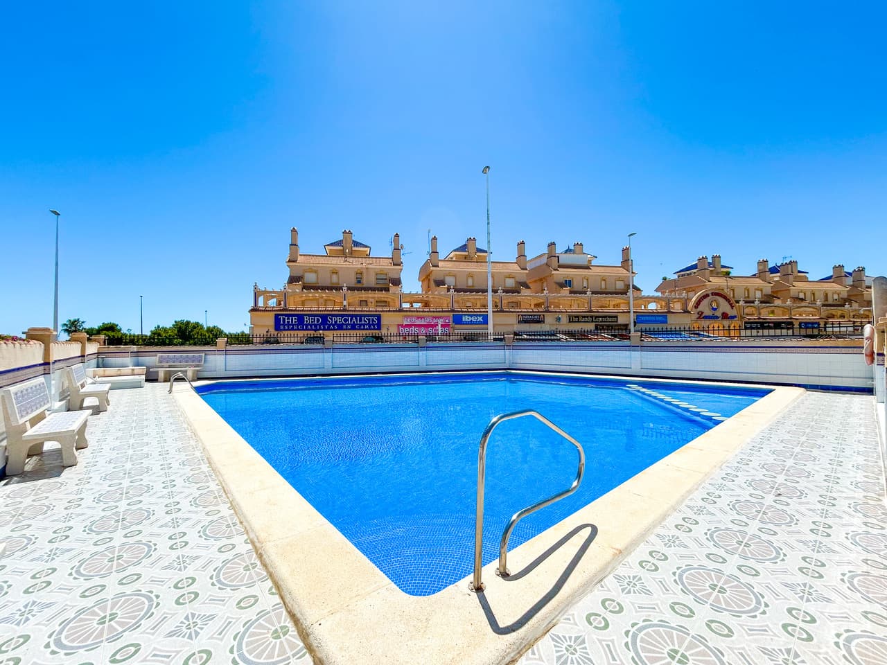 Located in the heart of La Zenia, this 2-bedroom, 1-bathroom apartment offers a blend of traditional style and a central location. The property is situated in a well-maintained building that includes lift access, a communal roof terrace, and a swimming pool. The interior features a functional open-plan layout with air conditioning and traditional character throughout. A private arched balcony provides sea views, while both bedrooms offer outlooks over a neighboring green park area. The apartment is within walking distance of local bars, restaurants, shops, and the beach, and is also conveniently close to La Zenia Boulevard, schools, and medical facilities. For leisure, several championship golf courses are reachable within a ten-minute drive. With easy access to the AP-7, the property is approximately 50 minutes from both Alicante and Murcia airports.