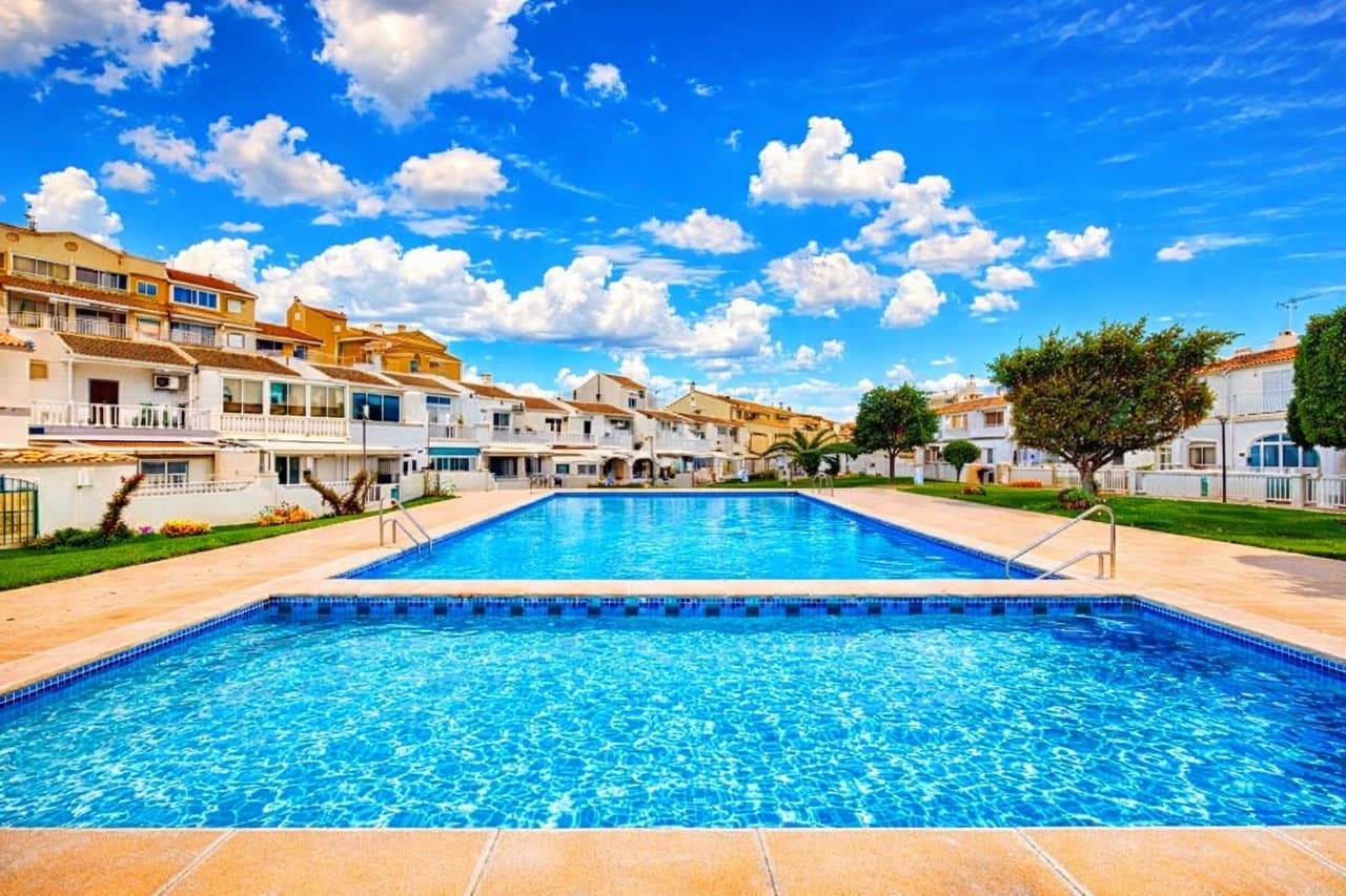 Nestled in the heart of Torrevieja, this charming 3-bedroom, 1.5-bathroom townhouse offers the perfect blend of sunshine, comfort, and Mediterranean living. With sunny gardens at both the front and rear, a private solarium, communal pool, and private parking, it’s an ideal home for holidays, full-time living, or a smart investment on the Costa Blanca.As you step through the gate, you’re welcomed by a bright front terrace — the perfect spot for morning coffee or relaxing afternoons — complete with a convenient awning for shade during the warm summer months.Entering through the front door, you’ll find a welcoming entrance hallway and the first bedroom, a versatile space ideal for a single bed, guest room, or home office. Continuing through the property, you arrive at a spacious and inviting living room that flows naturally into a well-sized kitchen, creating a comfortable space for both everyday living and entertaining.On this ground level there is also a convenient guest toilet, a practical utility room, and direct access to the sunny rear garden. From here you can step straight into the beautifully maintained communal gardens and pool area — perfect for cooling off on warm days.Upstairs, the property offers two generous double bedrooms and a family bathroom. One of the bedrooms provides access to the home’s private solarium, a wonderful sun-drenched space ideal for sunbathing, relaxing with a book, or enjoying warm Mediterranean evenings.With its sunny outdoor spaces, excellent layout, communal pool, and private parking, this delightful townhouse offers the perfect opportunity to enjoy the relaxed lifestyle Torrevieja is known for.