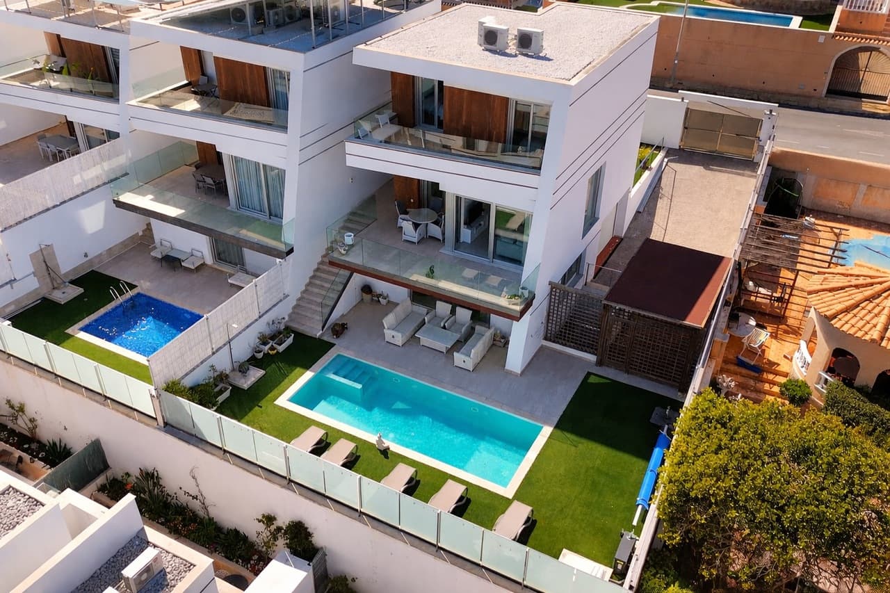Discover this impressive and modern villa, offering generous living space across four thoughtfully designed levels—perfect for both family living and entertaining.Upon entering the property, you are welcomed into a bright and spacious open-plan living area, seamlessly combining the lounge, dining space, and a sleek, fully fitted modern kitchen. From here, you have direct access to a private terrace overlooking the beautifully maintained garden and your own swimming pool—ideal for enjoying the Mediterranean lifestyle. This level also features a double bedroom with an en-suite bathroom, as well as a guest toilet.Upstairs, you will find two further double bedrooms. The master bedroom benefits from its own en-suite, while a separate family bathroom serves the remaining bedroom. This floor also enjoys access to a sunny terrace, perfect for relaxing in privacy.On the garden level, adjacent to the pool area, there is a fully equipped guest space complete with a small kitchen, bathroom, living area, and sleeping accommodation—ideal for visitors or extended family. This level also provides access to a large garage with ample room for both parking and storage.The lower ground floor offers a substantial basement area, currently used as additional guest accommodation. However, this versatile space could easily be transformed into a home gym, games room, cinema room, or any other lifestyle space to suit your needs. It also benefits from its own outdoor area with artificial grass.The property further features a private carport, with a driveway leading down to the garage, allowing for additional on-site parking.Spacious, stylish, and highly versatile, this villa is a fantastic opportunity for those seeking modern living with plenty of room to adapt and enjoy.