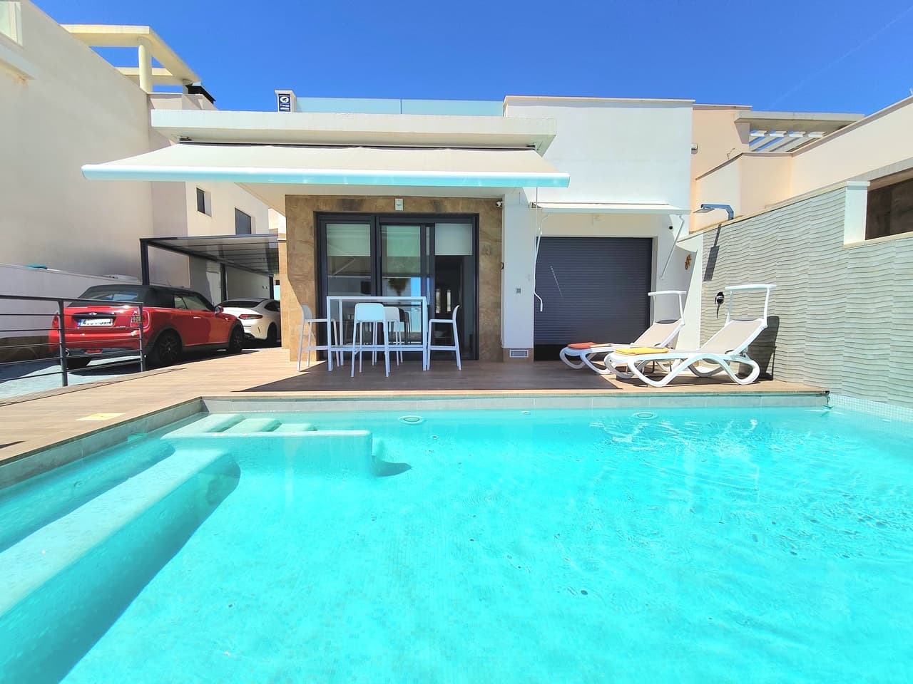 Designed for a comfortable balance of indoor and outdoor living, this contemporary three-bedroom, two-bathroom detached villa features a bright, open-plan living space. The lounge comes fully furnished with a reclining sofa and designer chairs, creating a welcoming area to relax. Adjacent to the living room is a fully equipped kitchen, fitted with high-quality Siemens induction appliances and sleek cabinetry, making it highly functional for daily living and entertaining.Both modern bathrooms benefit from natural light streaming through a feature skylight positioned directly over the shower. The main bedroom includes its own private en-suite bathroom, electric shutters, and an adjustable awning for tailored comfort. Built with sustainability in mind, the home is equipped with full air conditioning, infrared heating, and a 15-panel solar system with a 10 kW battery, keeping running costs low throughout the year. Security and convenience are well catered for with a private carport and an alarm system with four motion-detection cameras.The outdoor space spans 240 m² on a 300 m² plot, offering plenty of room to enjoy the Spanish climate. The terrace features a 4 x 7-metre salt-electrolysis swimming pool, complete with a built-in Jacuzzi, fountain feature and a Zodiac heat pump for year-round use. At the rear, the private garden provides a mix of sun and shade throughout the day, thanks to adjustable awnings that make it an ideal setting for outdoor dining and relaxation.The villa is situated 3 km from the local village centre and just a 10-minute drive from the coast's beautiful beaches. The popular Zenia Boulevard commercial centre is also only 10 minutes away, offering extensive shopping, dining, and entertainment options. Golf enthusiasts will appreciate the close proximity to several top courses, including the renowned Las Colinas Golf & Country Club.
