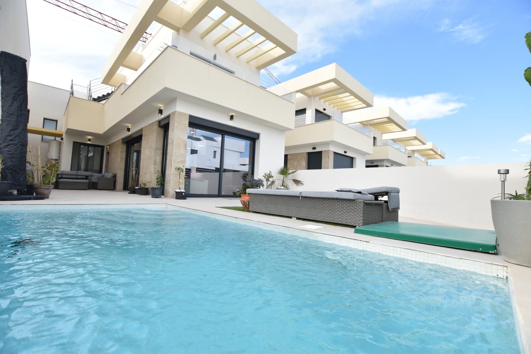 This modern detached villa, completed in 2025, is located in the well-established residential area of La Herrada, Los Montesinos. The property offers contemporary design, comfort, and a highly desirable location on the Costa Blanca.Upon arrival, the villa impresses with its clean architectural lines, private swimming pool, and off-road parking, providing both privacy and convenience.Inside, the home features a bright and spacious open-plan living area combining lounge, dining space, and kitchen, creating an inviting environment suitable for both everyday living and entertaining. A guest cloakroom is also located on this level.The master bedroom is situated on the ground floor and benefits from walk-through wardrobes and an en-suite shower room, making this layout ideal for those seeking main living accommodation on one level.Upstairs, there are two double bedrooms, both with built-in wardrobes and excellent natural light, along with a modern family bathroom. A generous terrace is accessible from this floor, offering additional outdoor space.From the terrace, external stairs lead up to the private rooftop solarium. This area provides open views across the surrounding countryside and both salt lakes, offering an ideal setting for sunbathing, relaxing, or outdoor dining.The villa is sold with most of the furniture included and is fully air conditioned throughout, allowing immediate enjoyment.The location is particularly convenient, with a local supermarket, bars, and restaurants within a five-minute walk. The beaches of Guardamar del Segura and Torrevieja are approximately fifteen minutes away by car, while Vistabella Golf is just a ten-minute drive.