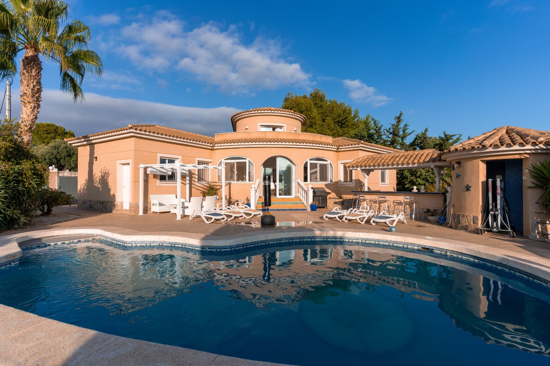 Beautiful villa in Busot with mountain viewVilla/estate with pool (built in 2001) with livable surface of 240 m2 and a 1.062m2 land plot is situated in the area Pisnella, Busot. Busot is a small and quaint 13 century medieval Spanish village situated only a few minutes drive away from the vibrant coast. El Campello, its nearest beach resort, is a mere 6 km drive, 20 min from Alicante airport. Close by amenities golf course Bonalba, Caves of Canelobre, Benidorm, Alicante Old Town.InteriorThe large villa, with fluid Spanish contours, has a modern and tasteful touch. The estate is surrounded with walls which give a great sense of privacy while still maintaining the views over the sea and mountains. The main building has an adjacent apartment, with separate entry, both exiting towards a large terrace. There is sufficient space to either enjoy the sun or shade. The views on the mountains and coastal line (direction Alicante) are breathtaking.The estate has 3 bedrooms with each its own bathroom. There are two completely furnished kitchen and two living rooms. Air Conditioning (warm and cold functions) can be regulated for each room separately. Fire place with ventilation for lumber fire. All windows are fitted with aluminum shutters, mosquito window nets, and all windows have double glass.Outside one can enjoy a large partially roofed terrace and a nicely formed designer swimming pool with its iconic logo. Alongside the pool there is a shower cabin with a toilet to rinse off. The terrace has a cozy bar with a decent amount of storage space and various kitchen facilities such as a sink and a fridge. The garden contains a stone barbecue and has lots of flora, including several beautiful palm trees. At the rear of the garden one will find a wooden cabin/shed for extra storage. The garage is large enough for a car, includes washing facilities and offers additional storage space.Interior Lower floor:Living room/salon 32m2 incl. Fireplace (satellite tv, phone and internet connection). Completely decorated kitchen 7m2 incl. dining bar fridge, freezer, oven, dishwasher, etc.Bath room 7m2 (shower, bath, double sink and own toilet)Bedroom 16m2 (room for large queen bed and enough room in its well designed built-in closets). Garage 16m2 (room for washing machine, dryer and storage)Tower level (1st floor):Salon/bedroom 29m2 (room for queen size beds with storage space built-in, access to own terrace). Bathroom 4m2 (sink, washing table, toilet)Terrace 8m2Ground Floor-adjacent apartmentSpacious Living room 17m2Kitchen 5m2 (large American style fridge, oven, washing machine and sink) Bathroom 4m2 (shower, double sink and toilet)Bedroom 9m2 (room for king size bed and build-in closets)Shaded Terrace (ground floor, outside)11m2 terraceSerre with views over the swimming pool, garden and the Spanish landscapes Swimming poolDesigner shaped swimming pool, well situated in a sunny area, and LED lightning Separate pool cabin with shower and toilet adjacent to the poolAround the pool you will find a large terrace with anti-slip tiles, space for pool beds and umbrellas. The low maintenance pool has several features for kids and has its own access to pump installation.GardenSub-tropical garden with many plant and tree varieties, including an automated plant watering installation. Many quaint terrace areas, including an open stone barbecue and exterior terrace bar with mini-kitchen.