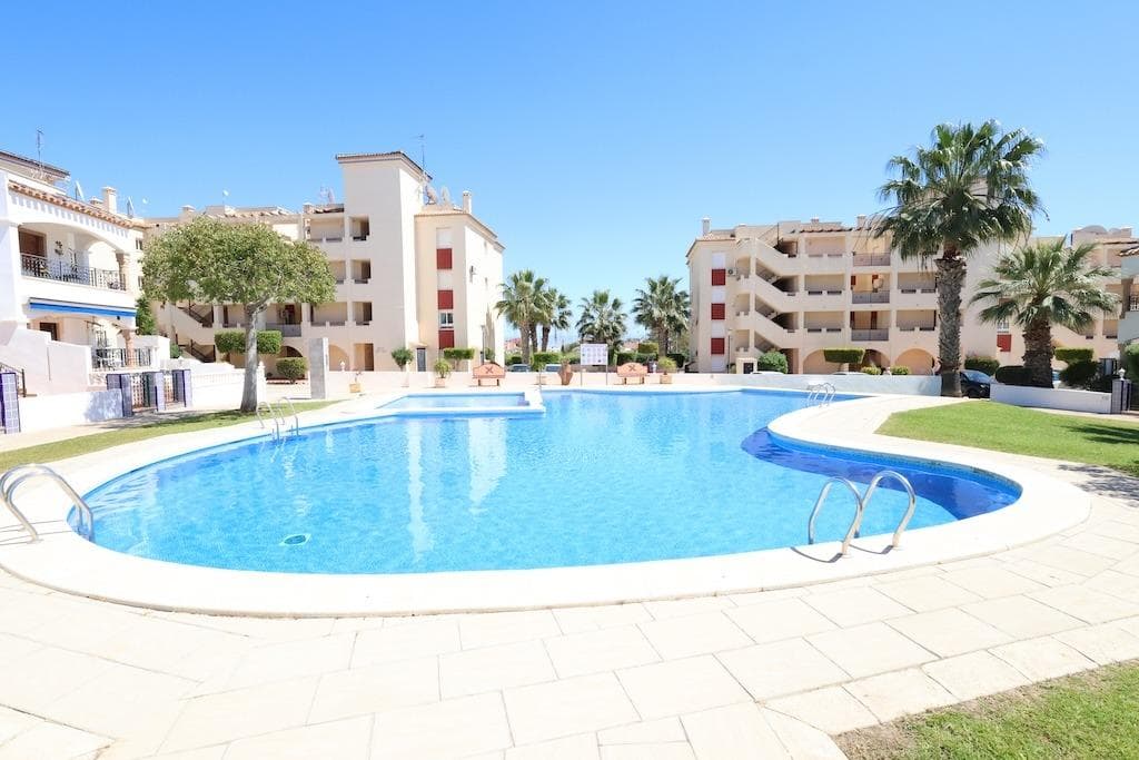 For sale a large two-bedroom, two-bathroom ground floor apartment is for sale. It's organized into a condominium with a swimming pool and lawn, located in the Jumia 2 development in Playa Flamenca. The apartment faces west, with access to the pool from the living room via the terrace and from the bedroom via the terrace. The apartment has 95 square meters of floor space and was built in a building dating back to 2001. The apartment consists of a small entrance hall, a spacious living room with a fully equipped American kitchen, two separate bedrooms with built-in wardrobes, and two full-size bathrooms, one of which is located in the master bedroom. It is sold furnished, with appliances included, and air conditioning in the living room.