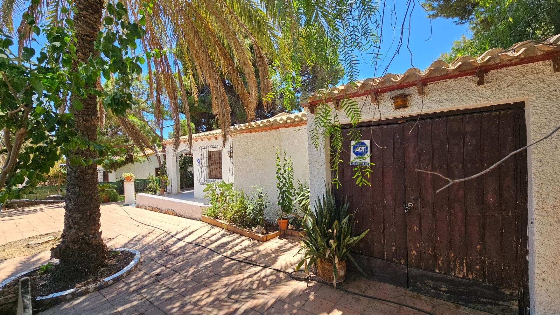 House for sale for renovation on a 600 m² plot, located just 300 meters from the sandy beach of Punta Prima in southern Torrevieja. Built in 1979 to a high standard, the property features spacious rooms, thick walls, and excellent sound insulation. The total built area is 150 m², with 120 m² of living space. The house consists of a large front terrace, a spacious living room with a fireplace, 2 bathrooms, a separate kitchen with a utility room, 3 separate bedrooms, and a patio lounge with stairs leading to a fourth bedroom. The corner plot measures 600 m² and includes a garden with swings, pine trees, palm trees, flowering shrubs, and a storage room. The property is sold with antique furniture. Arcostec can develop a renovation project for the existing house or provide a feasibility study for demolition and construction of a new villa. There is also an opportunity to purchase the adjacent 500 m² plot, increasing the total land area to 1,100 m². The price of the neighboring plot is €525,000