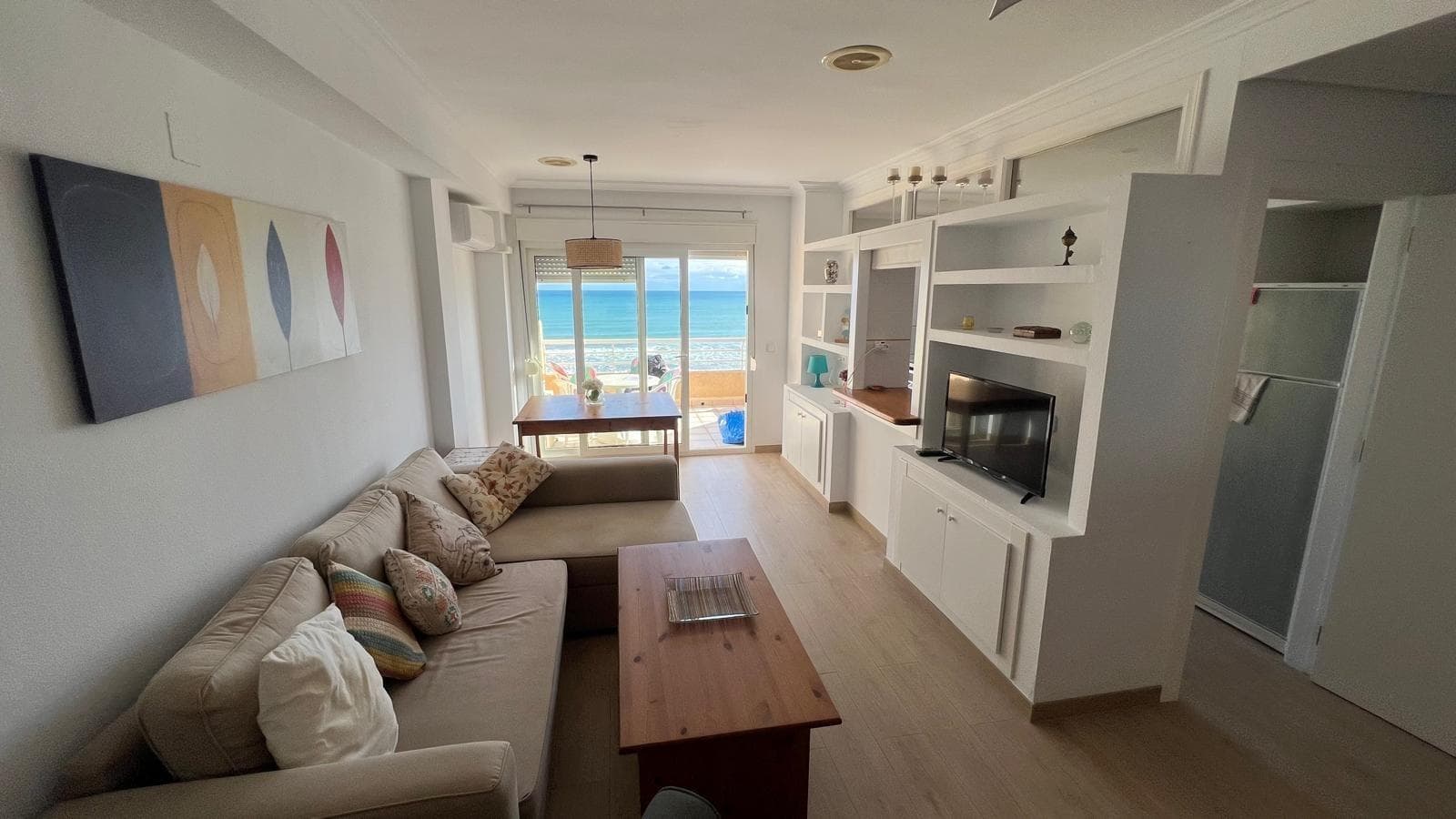 This beachfront penthouse in La Mata presents itself as an intimate and luminous retreat, designed for living facing the Mediterranean with a constant sense of seclusion and relaxation. Located at number 6 Calle Mayor, it integrates seamlessly into the heart of the small town of La Mata, with its coastal village atmosphere, terraces, local shops, and the tranquil lifestyle that characterizes this area north of Torrevieja. From the moment you enter the apartment, the presence of the sea influences everything: the light, the sounds, the breeze that flows in from the terrace, and the way every square meter is used to direct your gaze toward the horizon. It is a penthouse designed for one or two people who value the quality of the surroundings more than size, who prefer having breakfast to the sound of the waves rather than having soulless, unused square footage. The central element of the entire apartment is the terrace, which acts almost as another room, open to the sky and the sea, rising above the promenade and the golden sand of La Mata. By day, it becomes the place where most of the time is spent: a light table for breakfast in the sun, a couple of comfortable armchairs for reading or working on a laptop, and plants that add greenery to the dominant blue of the landscape. The Mediterranean opens up directly ahead, unobstructed, allowing you to contemplate how the sea changes with the time of day and the season: calm and bright in summer mornings, silvery in winter sunsets, and more intense and profound when the waves rise. The penthouse's height provides privacy from the promenade and the beach, so you can enjoy coastal life without sacrificing your privacy. As evening falls, the terrace transforms into a perfect setting for quiet dinners, candlelight, and leisurely conversations while the sky is painted in shades of orange and pink. The sound of the sea arrives softly, mingling with the distant murmur of the bars and restaurants along the seafront, creating a constant yet relaxing soundtrack that envelops the entire apartment. It's a space that invites you to entertain a couple of friends for a casual evening or to enjoy the silence and the breeze in solitude. In summer, this terrace practically becomes the house's living room, allowing you to spend most of the day outdoors, with the feeling of being on a private deck overlooking the sea. The interior of the house complements this privileged connection with the outdoors. From the living area, the intention to orient everything towards the terrace and the sea is clear, prioritizing light and visual continuity. Large glazed openings allow natural light to flood the main room for most of the day, reducing the need for artificial lighting and creating a warm, welcoming atmosphere that changes with the time of day. The ideal decor here is simple, clean, and functional, with few but well-chosen elements, letting the view outside take center stage. A comfortable sofa, a side table, and some low furniture are enough to structure the space without cluttering it. The kitchen, visually integrated into the living area or located in an adjacent, easily accessible space, is designed to serve a practical and relaxed lifestyle. It's not a kitchen intended for grand banquets, but rather for the everyday needs of a person or couple who enjoy preparing breakfasts overlooking the sea, light lunches after a morning at the beach, or simple dinners that are then enjoyed on the terrace. The proximity to the sea suggests a way of life where fresh fish, market-fresh fruits and vegetables, and Mediterranean cuisine set the pace. The kitchen becomes a comfortable and organized passageway, uncluttered yet ready to efficiently meet daily needs.