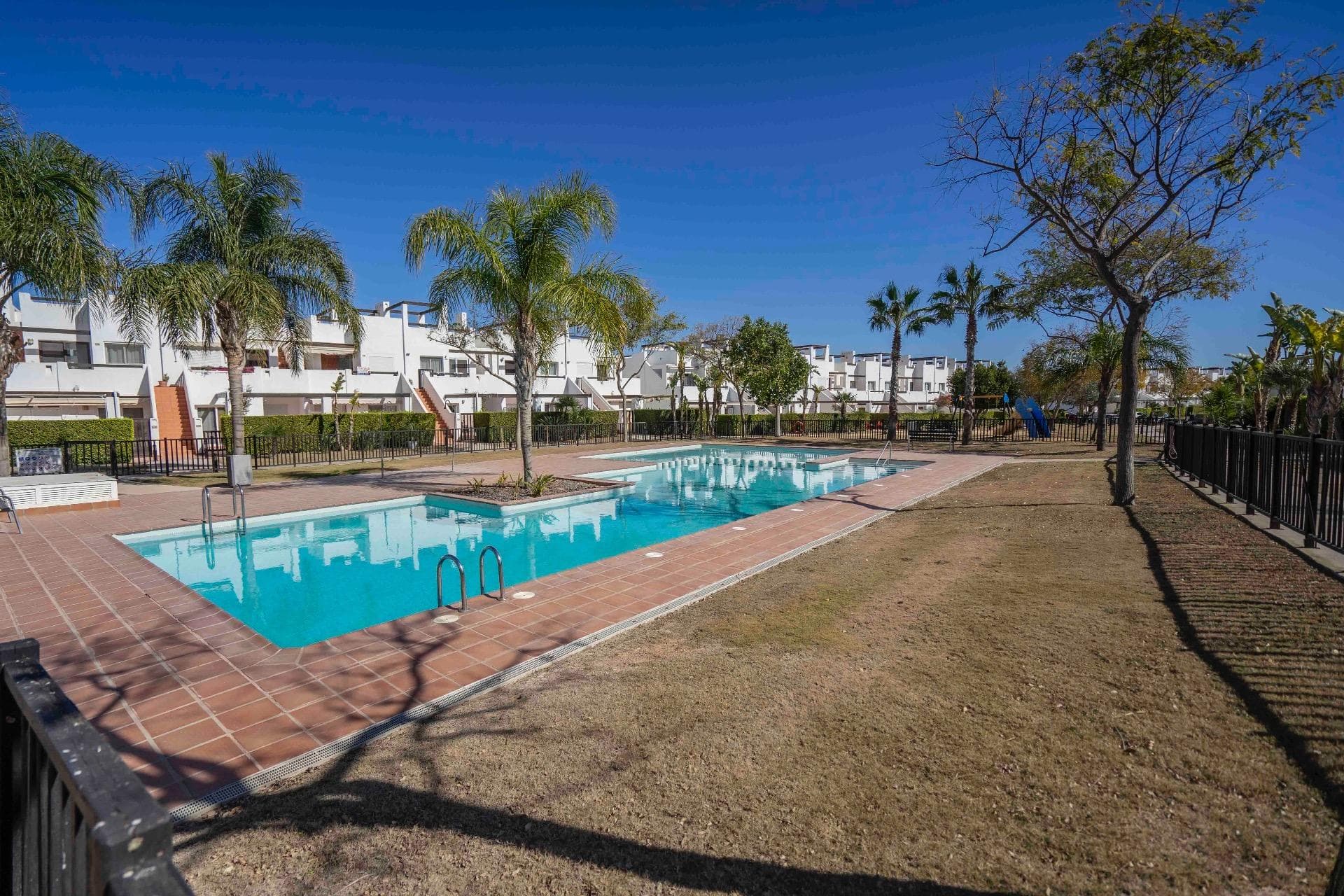 Located in the popular Naranjos 2 community within the highly regarded Condado de Alhama resort, this beautifully upgraded ground-floor apartment offers style, comfort, and versatility in equal measure. Originally designed as a three-bedroom property, the apartment is currently configured as a spacious two-bedroom home, with the third bedroom thoughtfully converted into an enlarged living and dining area. This flexible layout can easily be reinstated to a full three-bedroom configuration if desired. Presented in excellent, move-in-ready condition, the property enjoys a bright and contemporary feel throughout. The modern kitchen is finished with granite worktops, crisp white cabinetry, and almost-new appliances, creating a sleek yet practical cooking space. The generous living and dining area provides an inviting setting for relaxing or entertaining, while built-in wardrobes and two recently installed air-conditioning units ensure comfort and convenience year-round. The fully tiled bathroom features a stylish walk-in shower and quality finishes. Additional touches, including white door frames and a gas water heater, enhance the property’s fresh and modern appeal. Outside, the fully tiled private terrace offers the perfect space for outdoor dining or simply unwinding in the sunshine, complete with an awning for shade. A rare under-stairs storage area provides valuable extra space, ideal for bicycles, golf clubs, or beach equipment. Offered at €128,000, this exceptional apartment represents an ideal holiday home, rental investment, or permanent residence within one of the region’s most established and sought-after resorts.