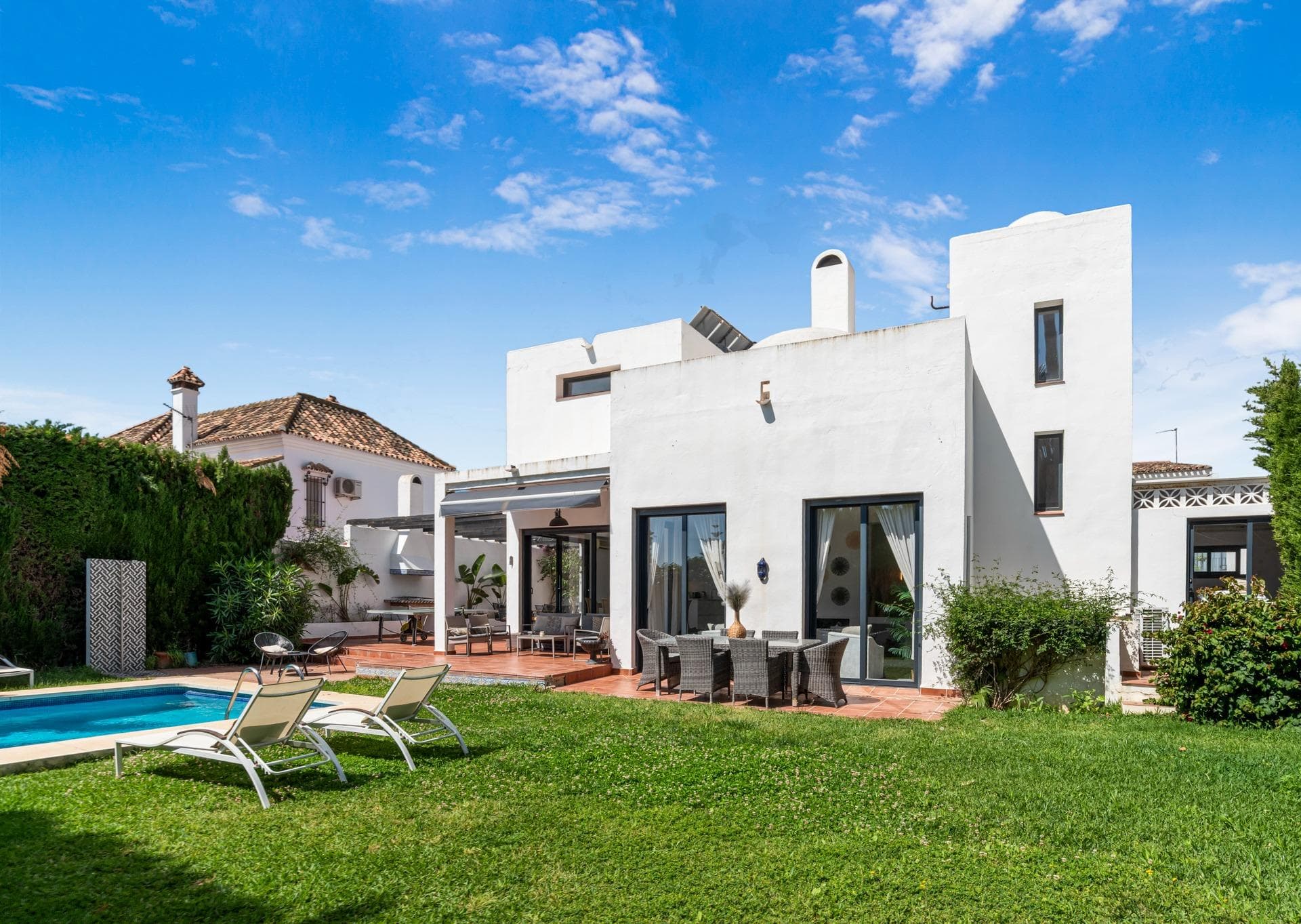 Welcome to Villa Rio Sena, a striking contemporary masterpiece ideally situated just moments from the Mediterranean shoreline and the world-renowned Puerto Banús. Seamlessly blending avant-garde architecture with refined comfort and exceptional investment potential, Villa Rio Sena represents a rare opportunity to acquire a premier lifestyle property in one of Marbella’s most coveted enclaves. Recently refurbished to the highest standards, the villa boasts sophisticated, light-filled interiors and fluid, open-plan spaces designed to celebrate the ultimate indoor-outdoor Mediterranean lifestyle. Spanning an impressive 291 m², the estate effortlessly accommodates up to 14 guests across 6 meticulously designed bedrooms—each featuring its own luxurious en-suite bathroom. This layout makes it equally perfect as an expansive family sanctuary, a venue for grand-scale entertaining, or a high-yielding asset for premium short-term rentals. The heart of the home is a luminous open-plan living area, complete with a cozy fireplace, a 65” Smart TV, and captivating views over the manicured grounds. The elegant dining space flows naturally into a sleek, state-of-the-art kitchen, fully equipped with premium appliances, a central island, and breakfast bar seating—masterfully crafted for both casual mornings and culinary hosting. Outside, the property transforms into a private oasis. A generous covered terrace hosts multiple chic lounge and dining zones, perfect for al fresco entertaining year-round. Complete with a built-in barbecue area, table tennis space, and lush, professionally landscaped tropical gardens, the exterior centers around a pristine swimming pool offering absolute privacy and tranquility. The location is unparalleled. Positioned within easy walking distance of the beach and Puerto Banús, residents enjoy immediate access to Marbella’s finest beach clubs, designer boutiques, Michelin-starred dining, and vibrant nightlife. Furthermore, a premier gym and padel club are located just steps away, making this villa a dream for wellness and sports enthusiasts. Whether envisioned as a sophisticated permanent residence, an exclusive holiday retreat, or a lucrative addition to a luxury property portfolio, Villa Rio Sena delivers the pinnacle of modern Marbella living in an unbeatable Costa del Sol location.