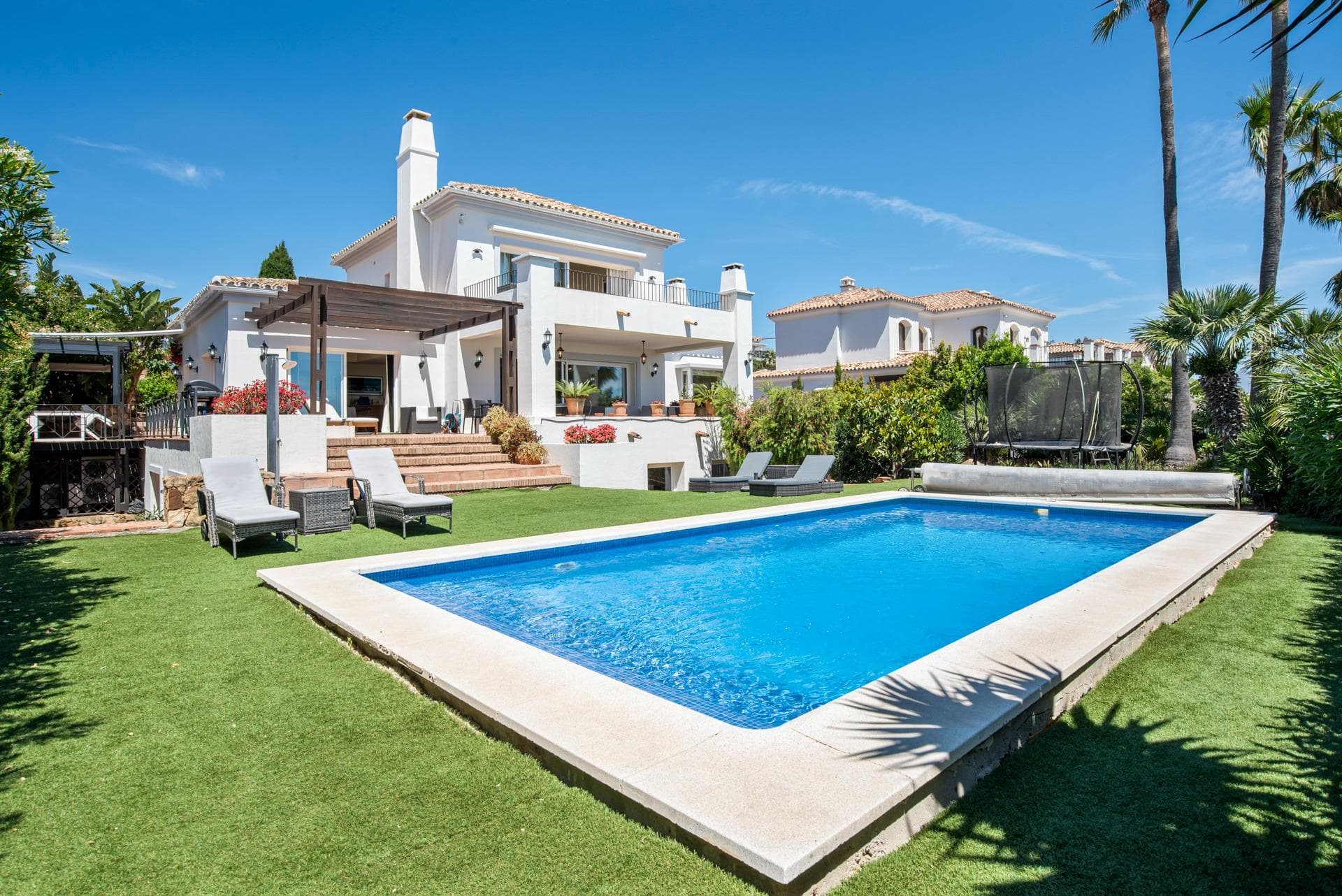 Nestled in the prestigious hillside enclave of La Paloma—perfectly positioned between the glamour of Sotogrande and the charm of La Duquesa—this elegant 4-bedroom, 5-bathroom villa epitomizes upscale Mediterranean living. Designed with an emphasis on privacy, light, and effortless entertaining, the property commands breathtaking, panoramic views of the sea and the southern Spanish coastline. Spanning three beautifully curated levels, the estate is perfectly versatile as a grand family residence, an idyllic holiday sanctuary, or a high-yielding luxury rental investment. The Top Floor Master Sanctuary: The entire upper level is dedicated to an opulent primary suite. This private retreat features an emperor-sized bed, a generous walk-in wardrobe, and a spa-like en-suite bathroom complete with a walk-in shower and jacuzzi bath. Large glass doors open onto a private terrace with commanding coastal views. The Main Living Level (The Heart of the Home): A sun-drenched, open-plan lounge flows seamlessly onto the manicured gardens and pool deck, blending indoor and outdoor living. This floor hosts a massive dining area, a fully equipped gourmet kitchen, a separate guest powder room, and a spacious double bedroom with its own en-suite bathroom. The Lower Wellness & Guest Level: An exceptional, self-contained living space ideal for guests or extended family. It features a second lounge with oversized lounge seating, two additional double bedrooms (both with en-suite walk-in showers), a dedicated remote-work hub, and a private wellness sauna. An Outdoor Paradise: The exterior is designed to maximize Andalusian outdoor living. At its center is an 8 x 4 meter swimming pool with easy-step entry. The grounds boast multiple curated zones: a covered main terrace with an oversized U-shaped sofa seating 10, multiple shaded alfresco dining areas for long summer lunches, and a lush lawn complete with a children's trampoline zone. Premium Extras: The property includes dedicated work-from-home spaces throughout, private gated parking, a secure garage, and ample street parking. The Location: Unbeatable proximity to pristine sandy beaches, world-class championship golf courses (including Valderrama), and vibrant marinas. Málaga Airport is just an hour away, with Marbella and Gibraltar an easy commute.