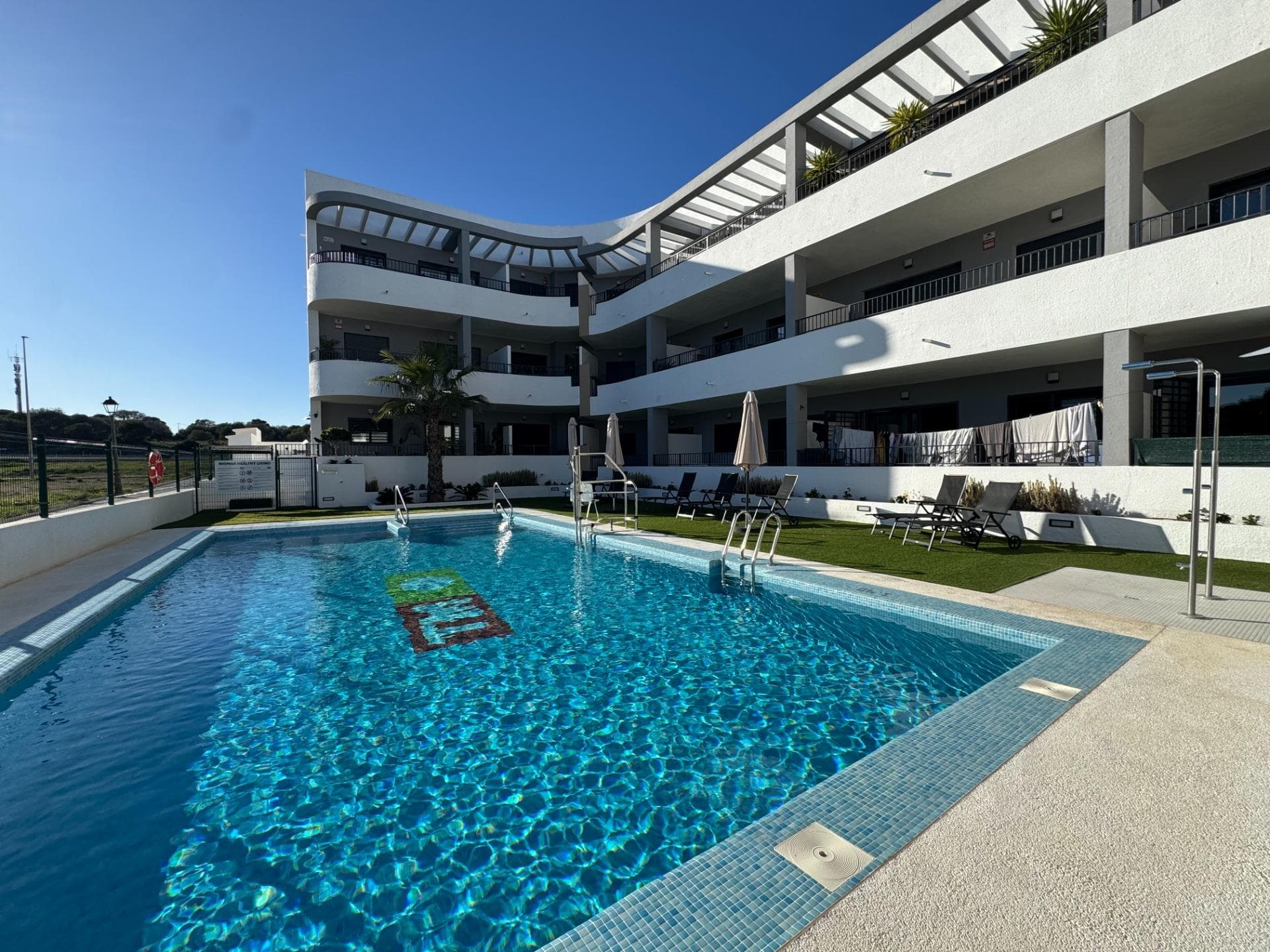 Elegant Ground-Floor Living in Mil Palmeras Discover refined coastal living in this beautiful 65 m² ground-floor corner apartment, where comfort, accessibility, and style come together effortlessly. Designed to be fully accessible for people with reduced mobility, this home offers ease and elegance for every stage of life. The apartment features two stylish and comfortable bedrooms and a modern, fully equipped bathroom, creating a welcoming and harmonious living space. Thanks to its corner position and dual east–south orientation, the property is bathed in natural light throughout the day, allowing you to enjoy both the gentle morning sun and warm southern exposure. Step outside into your private garden, a charming outdoor oasis ideal for morning coffee, relaxed lunches, or quiet evenings surrounded by greenery. Set within a prestigious and well-maintained residential complex, residents enjoy access to a communal swimming pool, sun terrace, and a fully equipped gym. The golden beaches of Mil Palmeras are just five minutes away by car, offering the perfect balance between tranquility and the Mediterranean lifestyle. The apartment is presented in excellent condition and ready to move into, featuring air conditioning and built-in wardrobes for maximum comfort and functionality. A private parking space and storage room are included, ensuring convenience and peace of mind. A rare opportunity to own a bright, accessible, and elegantly designed home close to the sea.