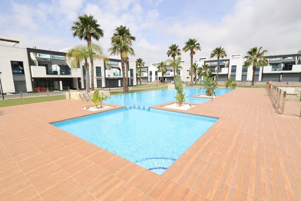 Located in El Raso, Residencial Oasis Beach XI, this South-facing second-floor bungalow features 77 sqm of built area with 2 bedrooms (1 en-suite), 2 bathrooms, a spacious open-plan living and dining area with an integrated kitchen, a terrace, and a full-floor private solarium with a pergola overlooking the communal pool. The property is sold fully furnished, includes air conditioning and an underground parking space. The residential complex offers 2 communal pools, mini-golf, a children's playground, and a wellness area with a sauna and jacuzzi.