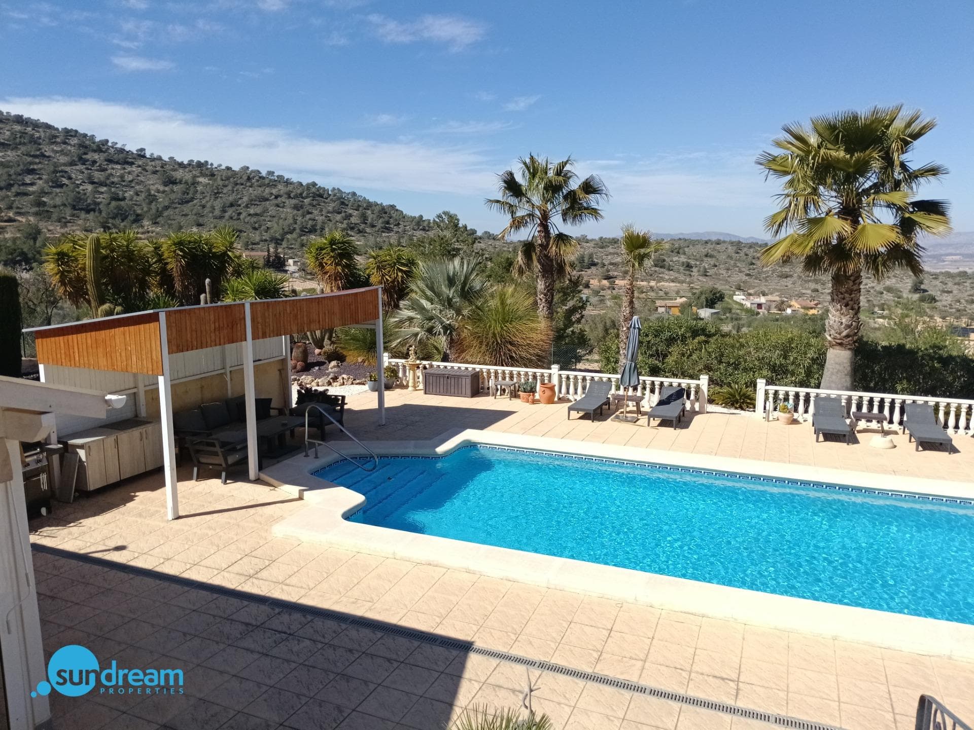 Charming Countryside Villa in La Zarza - El Pinoso with Heated Pool and Spacious Ground Nestled in the peaceful countryside of La Zarza, close to Pinoso, this charming detached villa perfectly combines rural beauty with modern comfort. Surrounded by open mountain views and unspoiled natural landscapes, the property offers privacy, generous space, and an authentic Mediterranean lifestyle — all within comfortable reach of the coast. Set on an impressive 8,521 m² plot, the villa enjoys a southwest orientation, bathing the home and its terraces in natural light throughout the day and delivering spectacular sunsets in the evening. The beautifully maintained grounds feature mature gardens, inviting outdoor living areas, and peaceful corners designed for relaxed country living. The property offers a total built area of 202 m² with a warm and welcoming layout. Inside, there are four bright bedrooms — one currently used as a home office — and two full bathrooms, one of which is en-suite. The recently renovated open-plan designer kitchen, fitted with high-end electrical appliances, flows seamlessly into the spacious living-dining area, creating a practical and elegant heart of the home. A traditional fireplace adds charm and comfort during the cooler months, while central heating and air conditioning ensure year-round wellbeing. The villa is sold fully furnished and ready to move into. Sustainability is also a key feature, with 16 solar panels providing electricity and 4 additional panels dedicated to pool heating. The exterior truly elevates this property. A private 12-metre heated swimming pool allows for year-round enjoyment. The pergola with outdoor kitchen, built-in barbecue, and bar area is ideal for entertaining family and friends. A bright winter garden provides the perfect setting for al fresco dining or simply unwinding while overlooking the peaceful surroundings. The plot is beautifully landscaped and includes a charming cactus garden, olive trees, and almond trees, enhancing the authentic Mediterranean atmosphere. Additional features include private parking, a wooden storage shed, and a spacious 30 m² storage/ workshop room located beneath the terrace. Conveniently located: Just 12 minutes from local amenities, shops, and restaurants 60 minutes from Mediterranean beaches 60 minutes from the international airport Whether as a permanent residence, a holiday retreat, or a rural tourism investment, this villa in La Zarza offers a rare opportunity to enjoy tranquility, nature, and comfort in one exceptional setting.