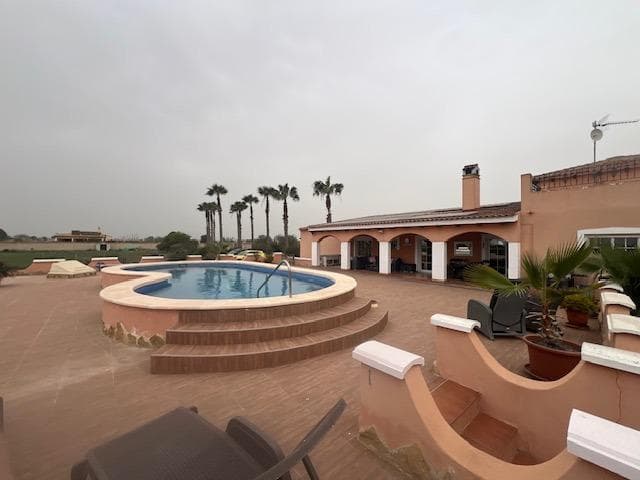 Stunning country house in Dolores, ALICANTE with 3 double bedrooms, 2 bathrooms, 2 walk-in wardrobes, lounge/diner with fireplace  open kitchen, separate preparation kitchen, study andsecond lounge with access to decking area to the garden. The villa is on a fenced plot of 6,300m with a 10 x 5m pool with large terrace surround. Ideally situated in a peaceful rural setting although close to town and only 15 mins’ drive to beaches and 35 mins to the airport of Alicante/Elche. Enjoy the superb views from the rooftop sun terrace. Mains water and electricity via solar panels with back up generator.