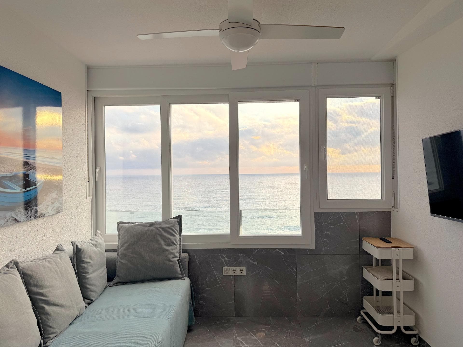 A rare opportunity to purchase a fully renovated apartment on the front line of the sea in one of the most sought-after areas of Torrevieja. The Miramar XII complex is located in Cabo Cervera, a quiet residential area with direct access to the sea that combines tranquillity with proximity to all necessary amenities.  The main advantage of this apartment is its unique location. The sea is just 10 metres away, the sandy beach around 50 metres. These are not side or partial views, but full frontal views of the Mediterranean Sea directly from the living room. The south-facing orientation of the apartment ensures maximum sunlight throughout the day: mornings are bright and warm, and evenings offer the chance to watch the sun paint the sea surface in golden hues.  Such apartments rarely come up in this complex, as most are oriented towards the interior or have only partial views. A south-facing aspect with direct sea views is exactly what buyers are looking for and what is valued in the rental market.  The Cabo Cervera area enjoys steady demand both from buyers seeking permanent seaside living and from investors focused on tourist rentals. It is quiet here, with no noisy bars or nightclubs, yet supermarkets, pharmacies, restaurants and public transport stops are all within walking distance. The centre of Torrevieja can be reached in just a few minutes by car or by using public transport.  The apartment has undergone a complete renovation with replacement of all utilities and finishing materials. This is not a cosmetic update or a budget refurbishment for letting purposes — it is a thorough reconstruction, done properly and built to last. One need only look at the photographs to appreciate the level of workmanship: quality tiles, solid plumbing, well-considered details. Everything has been done solidly, using materials that will not need replacing after a couple of seasons.  The air conditioning system has been completely replaced — a new LG air conditioner with inverter control has been installed, providing comfortable temperatures both in summer heat and during the cooler winter months.  The kitchen is fully equipped: new furniture has been installed, the worktop is made of stone, the stainless steel sink is undermounted, and the tap is modern and chrome-plated. Next to the sink there is a draining area. Kitchen sockets are installed for connecting appliances — everything has been thought through.  The bathroom has been completely refurbished and looks like something from a premium new-build development. The walls and floor are clad in large-format tiles with a white marble effect, which visually expands the space and gives the room a sense of cleanliness and light. A shower cabin has been installed with sliding glass doors and a thermostatic mixer tap allowing precise temperature control. The wall-hung vanity unit with basin has ample storage space, and above it is a mirror with integrated LED perimeter lighting.  For hot water supply, a Ferroli electric water heater with digital control has been installed. This is reliable European-made equipment that ensures a stable hot water supply and allows energy consumption to be monitored.  The apartment includes a separate bedroom and bathroom. One needs to understand the specifics of such coastal complexes: bedrooms here are traditionally compact, as the main living area is given over to the lounge zone with access to the sea. This is a characteristic feature of coastal apartment architecture, where the emphasis is on views and proximity to the water rather than bedroom size. That said, the bedroom is fully functional — it comfortably accommodates a double bed with bedside lamps and a chest of drawers for linen.  In the hallway there is a shoe cabinet and coat hooks, and on the floor is quality grey marble-effect tiling that runs throughout the apartment, creating a unified visual space. All furniture is new and included in the price of the apartment. The interior is decorated