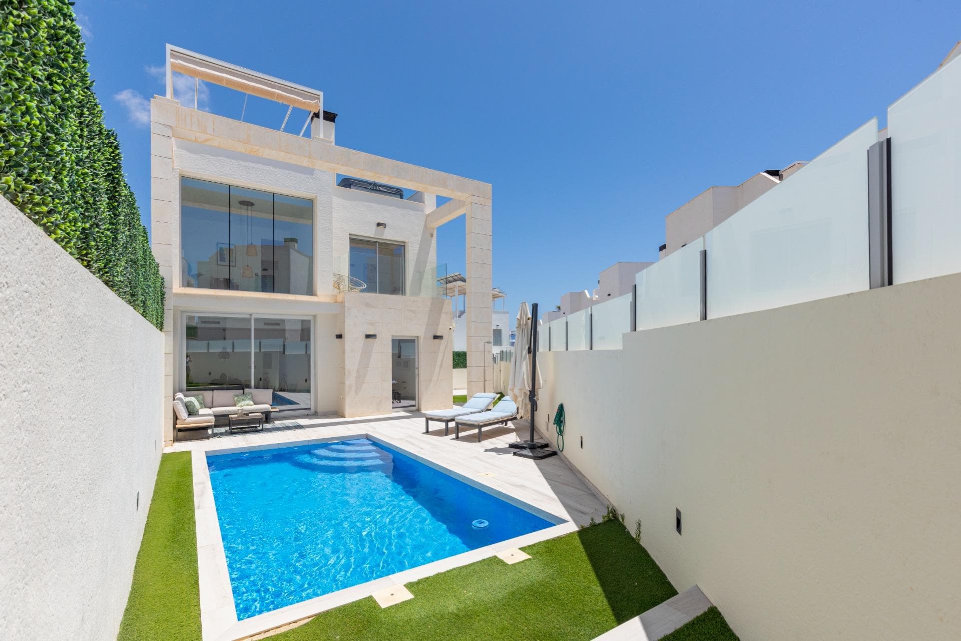 **Modern semi-new villa in Lomas de Cabo Roig, with private pool, huge basement and sea views from the solarium** Some homes are easy to show in five minutes. And then there are homes like this one — the kind you need to walk through slowly, because the best parts are not always obvious in the photos. This modern, semi-new villa is located in **Lomas de Cabo Roig**, a very practical and well-loved area: shops, restaurants, services, shopping centres and beaches are all just a short drive away, without being right in the middle of the noise. The house is set within a **gated residential complex**, which adds that extra feeling of privacy, security and peace of mind. But the first thing you notice when you walk in is the light. Light in the living room. Light in the bedrooms. Light everywhere. And especially in the beautiful **double-height living room** — spacious, elegant and full of character. This is not just “a nice lounge”. It is the kind of room that makes the whole house feel different. The property has **3 bedrooms**, comfortable rooms, a modern style and a layout designed for real everyday living, not just short holidays. And then there is the basement. A huge basement, currently used as a living area. It could be a cinema room, guest space, office, gym, games room… or it could easily be converted into a separate apartment if you want more independence for family or visitors. Outside, the house keeps getting better. You have a **private pool**, outdoor space to enjoy the Mediterranean lifestyle, and a **chill-out area on the solarium**, perfect for long sunny afternoons, quiet evenings or simply switching off. And from up there, yes — you also have **sea views**. A modern, bright and versatile home in a great location in Lomas de Cabo Roig. Not for someone looking for “just anything” near the coast. This is for someone who wants a comfortable, stylish home with real space, plenty of light and that extra something that makes it stand out. Shall we go and see it?