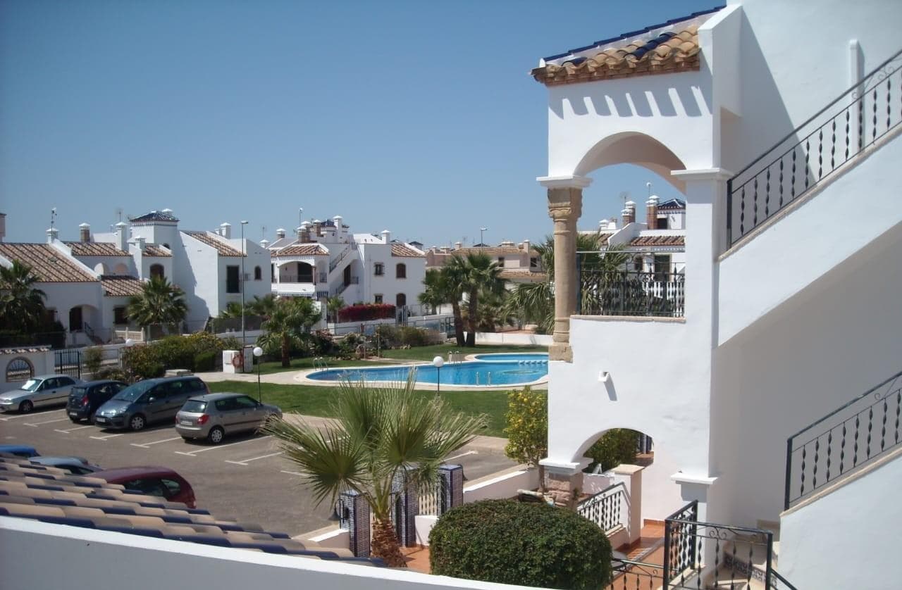 Discover this charming 2-bedroom duplex located in a private residential community, ideal as a permanent home, holiday property, or excellent investment on the Costa Blanca. A home full of character, spaciousness, and multiple outdoor areas to enjoy the Mediterranean climate all year round. The property offers two independent entrances: one from the landscaped garden area and another from the communal pool area, providing comfort and practicality. Both entrances feature spacious private terraces, perfect for relaxing outdoors. The main terrace has been extended and includes a practical storage room, ideal for sun loungers, bicycles, outdoor furniture, or beach items. A perfect place to enjoy breakfast in the morning surrounded by peace, tranquility and sun. Inside, you are welcomed by a spacious living-dining room with an elegant decorative stone fireplace, which also works perfectly to provide warmth during winter. The open-plan kitchen with breakfast bar creates a modern and very comfortable atmosphere. The property stands out for its quality materials: wood-effect windows and doors with double glazing, designed for excellent thermal and acoustic insulation. In addition, all openings have security bars. The home also benefits from central natural gas system for heating water and marble flooring throughout, adding comfort and elegance. On the ground floor there is also a guest toilet. On the upper floor there are two bedrooms. The master bedroom has direct access to a pleasant terrace with open views over the communal green area. The bathroom is spacious and fully equipped with bathtub and bidet. The southwest and southeast orientations allow excellent natural light throughout the day. One of the main highlights of this home is its spectacular private solarium, very spacious and with lovely views of the pool and communal gardens. An ideal space for sunbathing, gathering with friends, or enjoying unforgettable evenings thanks to its barbecue area and summer kitchen. All rooms and terraces face the interior of the community rather than the street, ensuring greater privacy and tranquility. The property is also located slightly further from the pool, avoiding noise and offering a more peaceful setting. The covered terrace with a beautiful natural vine creates fresh and welcoming shade, adding a unique Mediterranean atmosphere. The community features an impressive communal swimming pool and large communal parking area. A special property, ready to enjoy, full of charm, privacy, and excellent outdoor spaces.