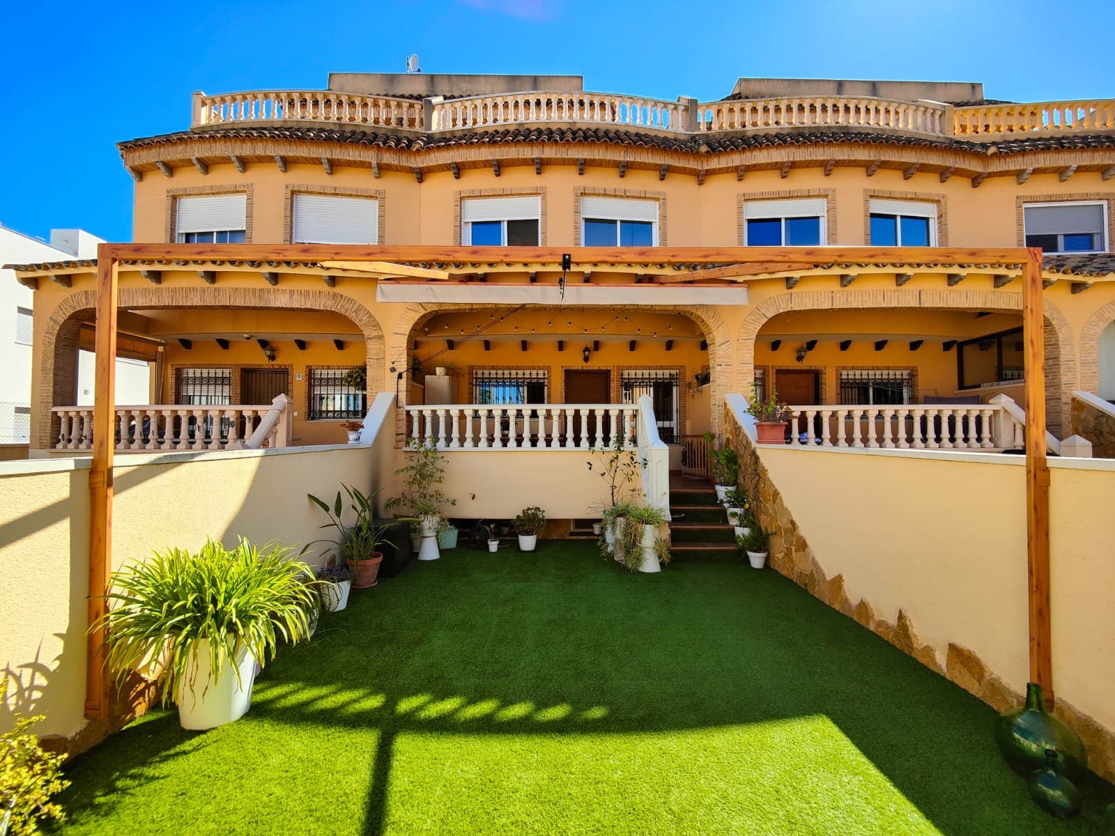Discover this beautiful partially renovated townhouse for sale in the peaceful Los Estaños area, within the Montegranados Residential complex in Guardamar del Segura. A spacious and bright property ready to move into, ideally situated just 2 km from the beaches of Guardamar and only 1 km from the town centre with all amenities nearby.The property offers 108 sqm built area distributed over several levels designed for comfort and practicality. The basement level features an additional living room, a full bathroom with shower and a convenient storage room, making it perfect as a guest area, entertainment space, an extra bedroom or storage.On the main floor, you will find a spacious and very bright living-dining area with a fully renovated open-plan kitchen in modern white finishes, equipped with stainless steel appliances and a dishwasher. There is also a guest toilet on this level. The grey laminated flooring throughout the property adds a contemporary and stylish touch.The first floor consists of 2 bedrooms and 1 full bathroom. The master bedroom benefits from plenty of natural light and includes two built-in wardrobes. The second bedroom has access to a covered interior patio currently used as a laundry area.The top floor features an additional room currently used as a home office, although it can easily be converted into an additional bedroom. From here, you have access to the private solarium with open views, ideal for enjoying the Mediterranean climate all year round.Outside, the property offers a 43 m² front garden with artificial grass and a lovely porch of approximately 15 m². The northeast orientation provides pleasant temperatures and natural light throughout the day.The property also includes a private parking space in the underground garage, air conditioning in every room, access to the communal swimming pool, and is sold partially furnished with appliances included.An excellent opportunity for permanent living, holiday use or investment on the Costa Blanca South. 
