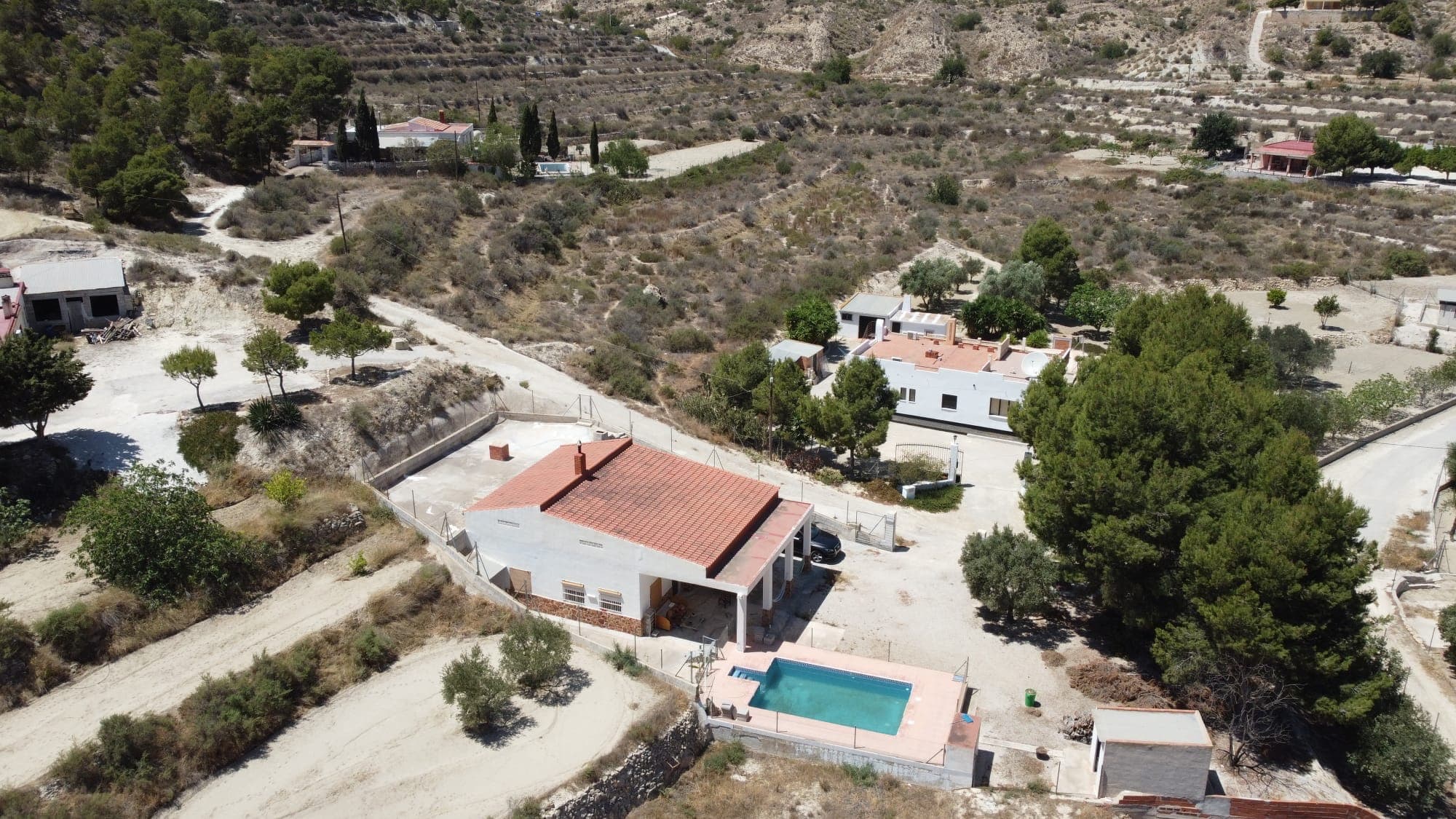 This property is in a quiet location with exceptional views of the surrounding mountains. It consists of 2 parts: a plot of 1676 m2 with all the constructions and a plot of 2400 m2 with 50 olive trees, lemon trees, tangerine trees, orange trees, fig trees, almond trees, gremadiers, peach trees, plum trees, vines... The built part has the house, a swimming pool (7x4), an oven/barbecue area and 2 storage sheds. The main house has already been partly renovated and is quite habitable in good condition. It consists of an open living room (30m2), 4 bedrooms, a completely renovated bathroom and a storage room. In front of the house is a spacious covered terrace of 50 m2 with views of the mountains and the pool. The house has a connection for water, electricity, internet with fiber optic, an air conditioning unit, fans and a wood stove. With a few inexpensive fixtures, we could make it a beautiful home. Less than 30 minutes from the beaches and airport of Alicante and 5 minutes from the town of Crevillente with all amenities.