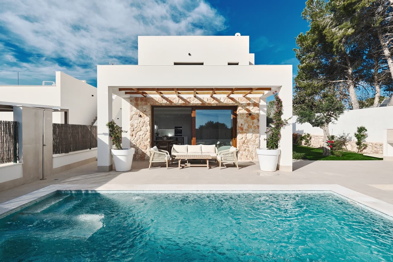 Discover contemporary Mediterranean living at its finest with this stunning key-ready detached villa, designed in elegant Ibizan architectural style and finished to an exceptional standard throughout. Situated in the highly sought-after residential area of Lomas de Don Juan, this modern home offers the perfect balance of privacy, comfort, and proximity to some of the Costa Blanca’s most beautiful beaches.The villa features three spacious double bedrooms and three stylish bathrooms, along with a separate guest WC, all thoughtfully designed to provide both functionality and comfort. With a build size of 137.63 m² set on a generous 425 m² plot, the property boasts a bright open-plan living and dining area that seamlessly connects to a fully equipped contemporary kitchen fitted with high-quality white goods. The home is fully furnished and includes air conditioning throughout, as well as carefully designed interior and exterior lighting, allowing you to move in and enjoy immediately.Attention to detail is evident in every aspect of the property, including underfloor heating in the living room and bathrooms, ensuring year-round comfort. Large terraces extend the living space outdoors, where a beautifully landscaped private garden surrounds a stylish 21 m² designer swimming pool, creating an ideal setting for relaxation or entertaining. The private solarium offers open views and sea views, providing the perfect space to unwind and enjoy the Mediterranean climate.Ideally located just a few minutes from the sandy beaches of Campoamor, La Zenia, and Cabo Roig, the villa also benefits from close proximity to the popular Zenia Boulevard shopping centre, as well as a wide selection of restaurants, bars, and supermarkets.This exceptional property combines modern design, high-quality finishes, and an unbeatable location, making it an ideal choice for a permanent residence, holiday home, or investment opportunity. Key-ready and fully equipped, it offers a seamless transition into luxury Mediterranean living.