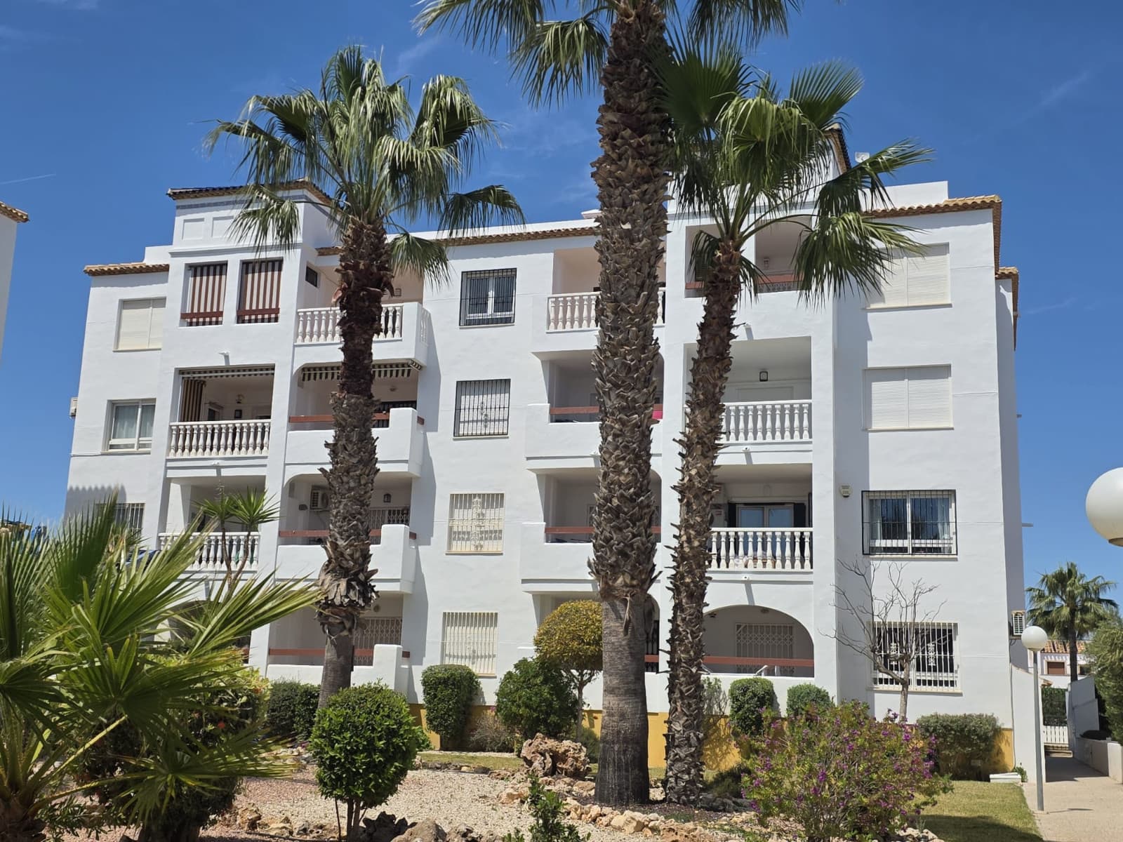 This bright and spacious corner penthouse is perfectly positioned in the highly sought-after Villamartin Pau-8 area in Orihuela Costa, offering an exceptional opportunity to enjoy the Costa Blanca lifestyle in one of the region’s most desirable locations. With 80 m² of living space, the apartment features two generously sized bedrooms, including a principal suite with a private en-suite shower room, and a guest bathroom with a bathtub, combining comfort and practicality for residents and guests alike.Flooded with natural light thanks to its corner position, the apartment boasts a private terrace overlooking landscaped gardens, providing an inviting space for al fresco dining, morning coffee, or simply soaking up the Mediterranean sun. The home has been freshly repainted and is offered unfurnished, allowing the new owner to personalise the interior to their taste. Additional features include cold/hot air conditioning, a fitted alarm system, and lift access for effortless convenience.Residents benefit from a gated community with a large, beautifully maintained communal swimming pool, landscaped gardens, a private fenced parking area, and access to an expansive rooftop solarium ideal for all-day sunbathing and relaxation. With community fees of just around €78 per month and council tax €450 , this property combines premium amenities with excellent value.The location is superb, just a 10-minute walk (approximately 800 metres) from Villamartín Plaza, renowned for its vibrant atmosphere and wide selection of restaurants, cafés, bars, and essential services. The penthouse is also ideally situated for golf enthusiasts, surrounded by four prestigious courses: Villamartín Golf, Real Club de Golf Campoamor, Las Ramblas Golf, and Las Colinas Golf. Within five minutes by car, you can reach the renowned Zenia Boulevard, offering over 150 boutiques, restaurants, and leisure facilities, as well as the golden sandy beaches of Orihuela Costa, celebrated for their crystal-clear waters. Alicante–Elche and Murcia-Corvera International Airports are both accessible within approximately 45 minutes via the A7 motorway, providing excellent connectivity for international travel.Combining space, privacy, and an enviable location, this distinguished penthouse is an ideal choice for a holiday home, permanent residence, or high-quality investment. With low monthly community fees and excellent amenities, it offers a hassle-free, premium Mediterranean lifestyle. Contact us today to arrange a viewing and secure this exceptional home in the heart of Orihuela Costa.