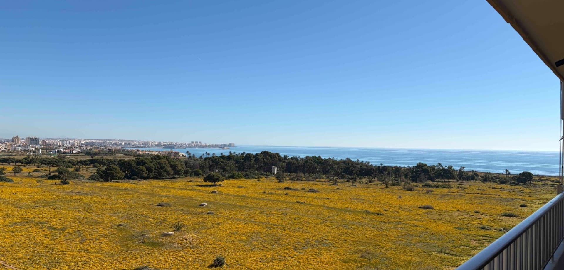 Located just 500 metres from the Mediterranean Sea, this fully renovated corner penthouse on the 6th floor offers privacy, natural light and panoramic views in one of the most prestigious areas of Punta Prima.The elevated top-floor position and corner layout provide open views of the sea, salt lakes, mountains and city skyline, with sunrises and sunsets visible throughout the year. The apartment benefits from excellent natural light and a strong sense of openness both day and night.The property has a constructed area of 70 m² and has been renovated to a high standard. All windows open directly onto the terrace, creating a seamless indoor–outdoor connection and eliminating internal patios. Panoramic sound-insulated windows ensure excellent acoustic comfort while maintaining open views.The interior features modern designer furniture, natural stone elements and large-format porcelain tiles. The fully equipped kitchen includes an induction hob and quality appliances. Comfort is ensured with inverter air conditioning with WiFi control, a programmable boiler and good insulation. The apartment is sold fully furnished and ready for immediate use.The building offers a lift and a communal swimming pool. A full façade renovation is currently in progress and has been fully paid, with no additional costs for the new owner. The apartment has a tourist license, and a new license can be reissued, as licenses are granted within this building.Gated communal parking with a roof is available on site. An optional underground parking space can be purchased for €10,000.