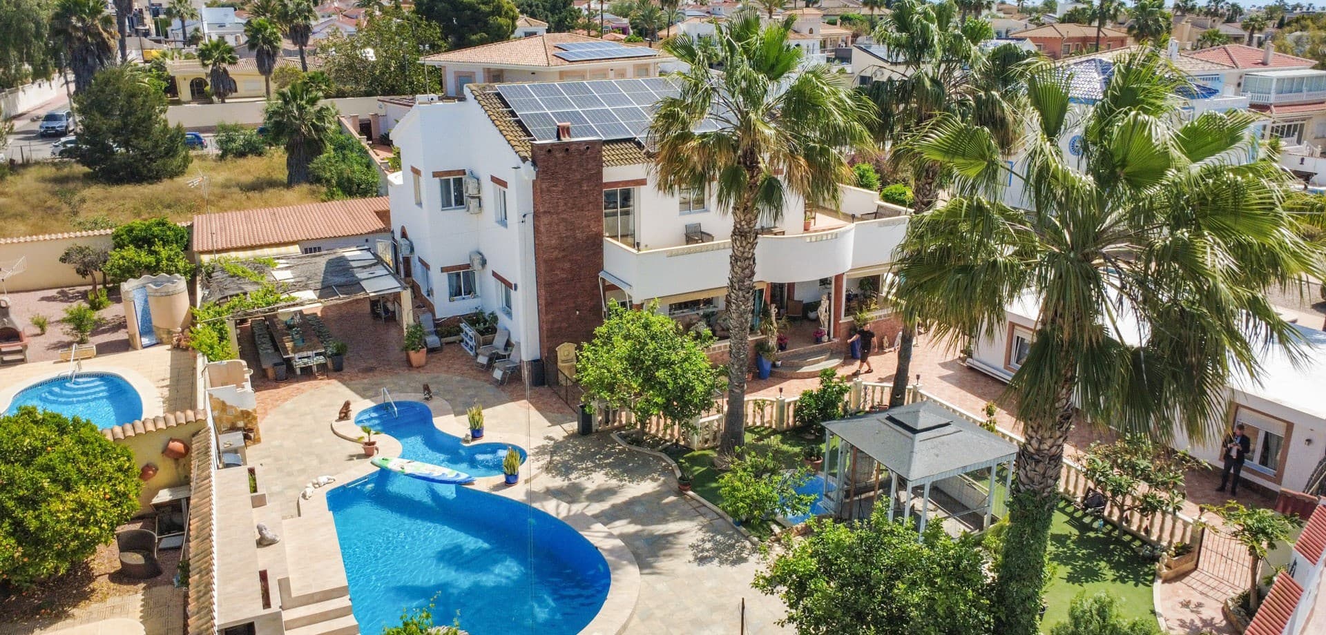 Located just moments from the vibrant main street of Ciudad Quesada, this exceptional villa offers a rare combination of space, privacy, and resort-style living — all within walking distance to restaurants, shops, and amenities.Set on a beautifully landscaped plot, the property features a main villa of approximately 360 m², designed for comfortable family living on a grand scale. Inside, you’ll find 5 spacious bedrooms, 2.5 bathrooms, a huge living room filled with natural light, a separate fully equipped kitchen, and a balcony — creating the perfect balance between indoor and outdoor living. Guest Accommodation & Investment PotentialIn addition to the main house, the property includes four independent buildings (approx. 120 m² in total), offering incredible flexibility and income potential:2 fully equipped guest houses, each with:Living roomKitchenBedroomBathroomPerfect for hosting family and friends or generating rental income in one of Costa Blanca’s most sought-after areas. Private SPA & Entertainment AreasThis villa truly stands out with its own private wellness and leisure facilities:Dedicated SPA building with:SaunaJacuzziRelaxing chill-out areaSeparate entertainment space, ideal as:Gaming roomLoungeStorageA perfect setup for enjoying year-round luxury living or creating a boutique-style retreat experience. Outdoor Living at Its FinestThe exterior of the property is nothing short of spectacular:Beautiful mature garden with:Fruit treesPalm treesLush greeneryA charming artificial river feature running through the gardenLarge tiled terrace areas for entertaining and sunbathingAnd the true centerpiece: