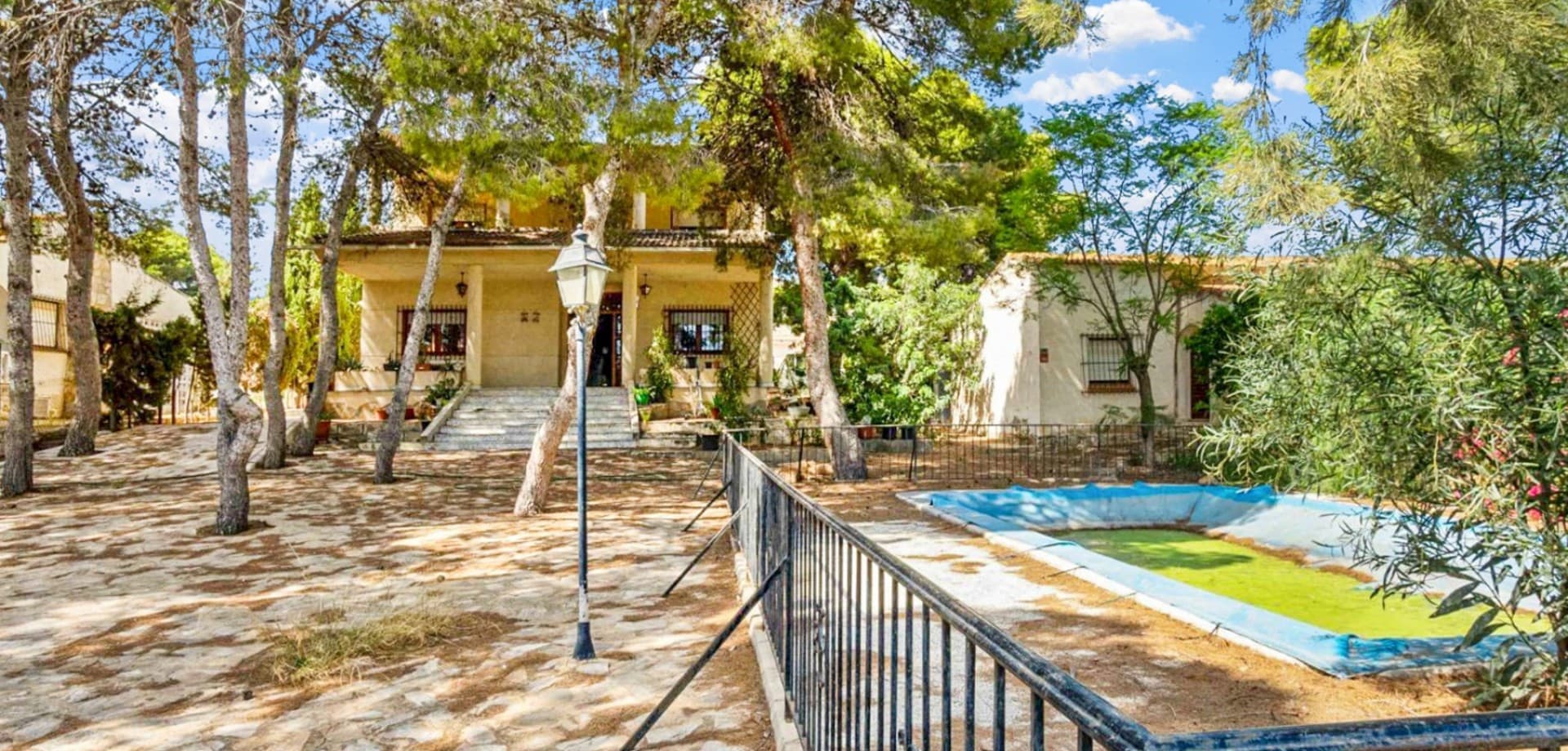 Set on an extraordinary 1,320 m² plot in one of the most desirable residential areas of the southern Costa Blanca, this unique independent villa in Los Balcones offers exceptional space, privacy, and endless potential for a large family home or luxury renovation project.Surrounded by mature Mediterranean gardens filled with beautiful vegetation and natural wildlife, the property enjoys a peaceful atmosphere rarely found so close to the centre of Torrevieja and the beaches of Orihuela Costa. Ancient pine trees, jacarandas, olive trees, palm trees, carob trees, loquat trees and many more species create a truly special environment full of character and charm.The main villa is distributed over two floors and offers spacious and elegant interiors throughout. On the ground floor, you are welcomed by a large covered terrace leading into an impressive entrance hall, a bright living and dining room featuring a high-quality marble fireplace, and a generous independent kitchen complete with pantry and utility gallery. This level also includes two double bedrooms with built-in wardrobes and two bathrooms, one of which features a walk-in shower.A stunning marble staircase with carved wooden handrails leads to the upper floor, where you will find four additional bedrooms with built-in wardrobes, a spacious bathroom with bathtub, and a large covered terrace overlooking the gardens and surrounding area.In addition to the main residence, the property also benefits from a separate semi-detached guest house with its own living room, kitchen, two bedrooms, bathroom, and covered terrace — ideal for extended family, guests, rental accommodation, or staff quarters.Outside, the villa features a large private swimming pool measuring approximately 4.20 x 8.20 metres, surrounded by extensive sunny terraces perfect for relaxing and entertaining. There is also a barbecue area, storage room, and multiple outdoor spaces to enjoy the Mediterranean climate throughout the year.Although the property would benefit from updating and modernisation, it offers extraordinary potential to create a truly spectacular residence in one of the best locations in Torrevieja.Los Balcones is highly regarded for its peaceful residential atmosphere while remaining close to all essential amenities, beaches, golf courses, shopping centres, schools, sports facilities, and the centre of Torrevieja.