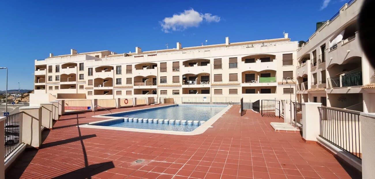 This light, bright and airy apartment set in the heart of the traditional spanish village of Sucina really has it all. Two bathrooms, sunny terrace, direct access to the swimming pool with all that the village has to offer. The apartment enters into a hallway which leads to the living room. To the left is the kitchen which is part open planned. The kitchen comes with fitted kitchen, ceramic hob, oven, extractor fan, washing machine, fridge freezer and it has a granite worktop, hatch or sort of counter to be served to the living room. The living room is a living dining area which is currently furnished with a dining room suite, sofa and armchairs, unit with TV, airconditioning and leads to a covered terrace with a very sunny orientation with  views over the village and over the Spanish countryside to the left. The living room leads to a small hallway. To the right is the main bathroom with bath tub, shower, WC and sink and a window. There is a hallway from the living room; to the left of the hallway is the second bedroom with twin beds, fitted wardrobe, ceiling fan, bedside cabinets. To the front of the hallway is the main master bedroom, which is a good-sized double room with a double bed, fitted wardrobes, bedside cabinets, ceiling fan, and it leads to an ensuite bathroom with WC, shower and wash hand basin.  The apartment comes with many extras; there is a storage unit on the main terrace, security grille on the front door, mosquito nets on the windows and the patio doors, extractor fan in the bathrooms, new hot water boiler, Wifi and airconditioning in the living room. This apartment is set in a building which has a large community pool, lift access, and it is situated very close to all amenities, just 20 minutes from the coast and 20 minutes to an airport. Highly recommended for viewing.