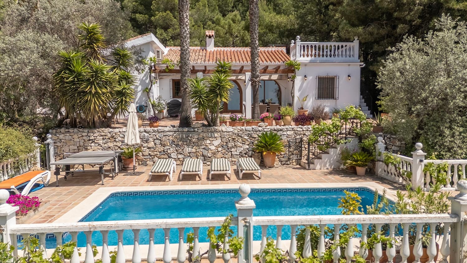 Unique Villa with Pool and Sea Views Welcome to this truly special villa, where authentic Andalusian charm meets comfort, privacy, and breathtaking views of both the mountains and the Mediterranean Sea. Here you will find a peaceful oasis with lush gardens, spacious terraces, a private pool, outdoor kitchen, and garage – all within walking distance of the charming village of Cómpeta. The villa offers 4 spacious bedrooms and 2 bathrooms, perfectly distributed with two bedroom areas at opposite ends of the house, creating an ideal layout for both families and guests. The heart of the home is the large and inviting living room with high ceilings, beautiful wooden beams, and a wood-burning stove, creating a warm and authentic atmosphere. The open-plan kitchen is connected to the living area, making it easy to socialize while cooking. From the living room, there is direct access to the beautifully landscaped terraces and the lovely pool area, where the spectacular mountain and sea views can be enjoyed all day long. At the entrance of the house, you will find a large enclosed terrace with a built-in barbecue and outdoor kitchen – the perfect setting for long summer evenings with family and friends. From here, there is access to a utility room with washing machine and additional storage space. The property consists of two plots with a total area of 5,242 m² and is surrounded by beautiful terraces, palm trees, and Mediterranean atmosphere. The property also includes a garage, storage room, and outbuilding. Perfect location: Walking distance to charming Cómpeta Easy access to the property Fantastic views of both the sea and mountains Ideal as a permanent residence, holiday home, or rental investment A rare property that truly must be experienced.
