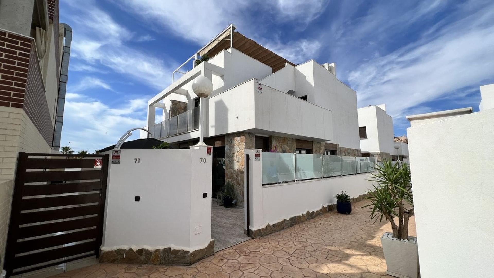 In Lomas de Cabo Roig, within the exclusive residential complex Residencial Sinergia World Fase III, you will find this charming semi-detached villa that invites you to imagine a peaceful life under the Mediterranean sun. Built in 2017 and enjoying a pleasant northeast orientation, the property offers approximately 85 m² distributed over two floors, along with a fantastic private solarium of around 35 m², perfect for enjoying the wonderful climate all year round. As you enter the home, natural light welcomes you into a cozy and bright living–dining area equipped with hot and cold air conditioning, an ideal space to relax or share special moments with family and friends. Next to it is a fully equipped open-plan French-style kitchen and a practical utility gallery. On this same floor there is also a comfortable bedroom with a large built-in wardrobe and air conditioning, as well as a complete bathroom with a walk-in shower, perfect for guests or for everyday convenience. Going up to the first floor, the property continues to impress with two spacious bedrooms, both with built-in wardrobes and air conditioning, offering a peaceful and comfortable environment for rest. On this level you will also find another full bathroom with a walk-in shower and a pleasant terrace that serves as a prelude to the private solarium. This generous rooftop space, equipped with an awning and a summer kitchen, becomes the perfect place to enjoy long afternoons outdoors, relax under the Mediterranean sky or share unforgettable moments with family and friends. Outside, the property features a large corner tiled garden of approximately 45 m², ideal for making the most of the sunny days, hosting outdoor meals or simply enjoying the tranquility of the surroundings. The residential complex, private and well maintained, offers excellent communal areas including a swimming pool, gym and sauna, creating a comfortable and exclusive environment for its residents. In addition, the property includes a spacious private underground parking space and a practical storage room of approximately 8 m². The home is sold fully furnished and equipped, ready to move into and start enjoying from the very first day. All of this is set in an excellent location, close to all amenities, just 2.5 km from the beach, 3 km from several golf courses and approximately 45 minutes from Alicante Airport. The community fees are €660 per year and the property tax (IBI) is €360 per year.