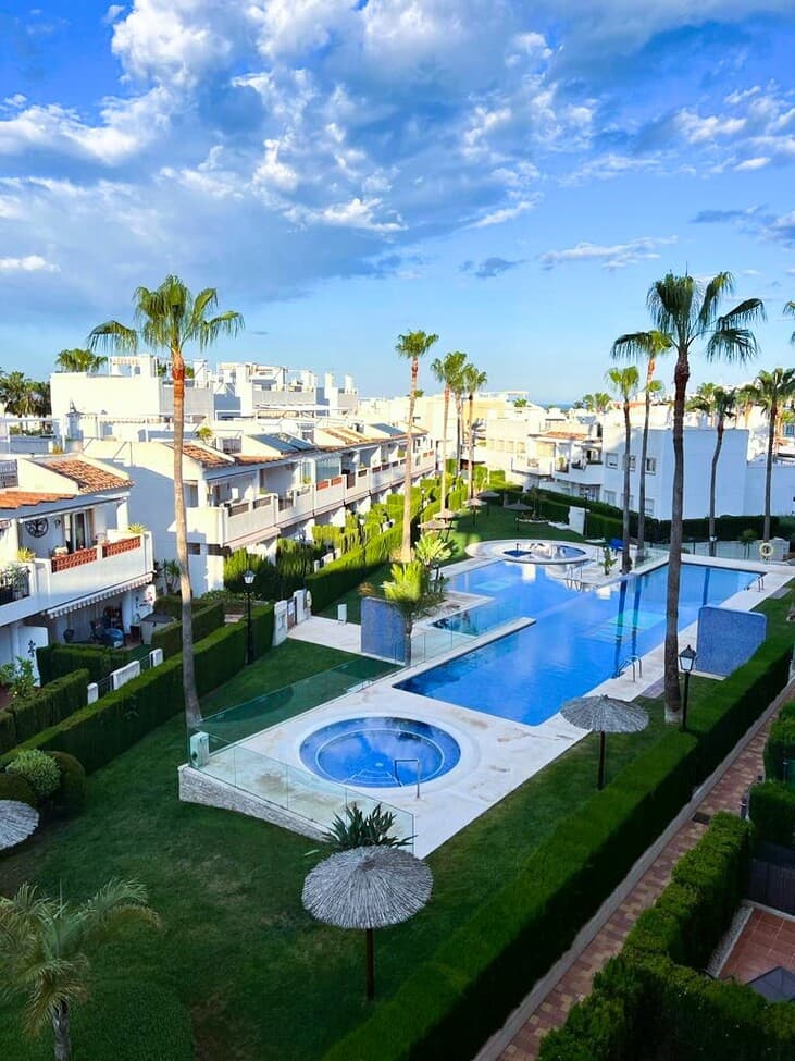 This ground-floor apartment comprises three bedrooms, two bathrooms, and a living room with an open-plan kitchen. The living room opens onto a terrace with a garden. A utility room is also located off the kitchen. The property is sold furnished, with appliances and ducted air conditioning. A designated above-ground parking space is included in the complex. The complex offers a large swimming pool, a jacuzzi, and green areas. The location is close to the La Fuente and Villamartin Plaza shopping centers, several supermarkets, bars, and restaurants.